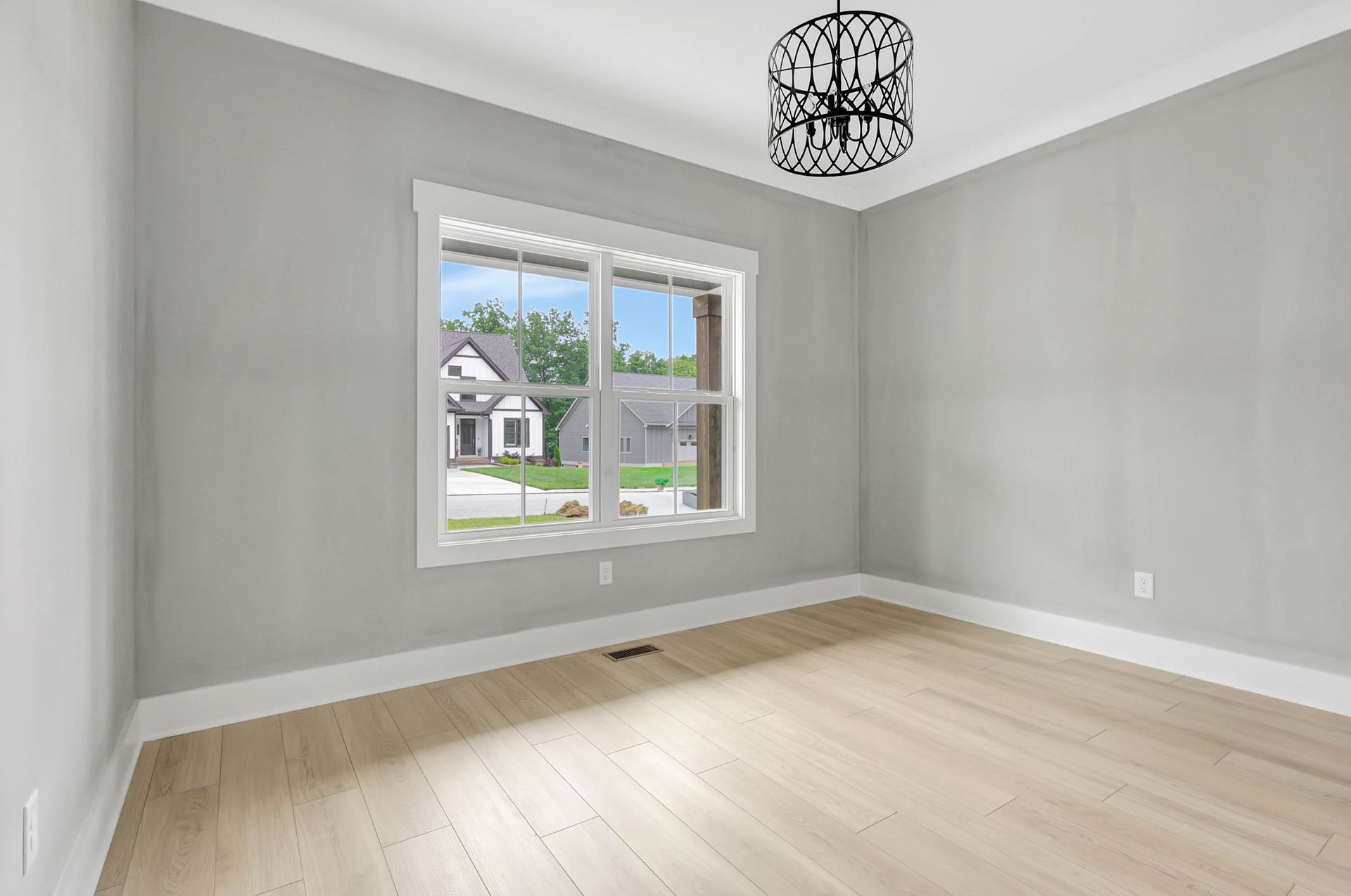 An empty room with a large window and a chandelier.