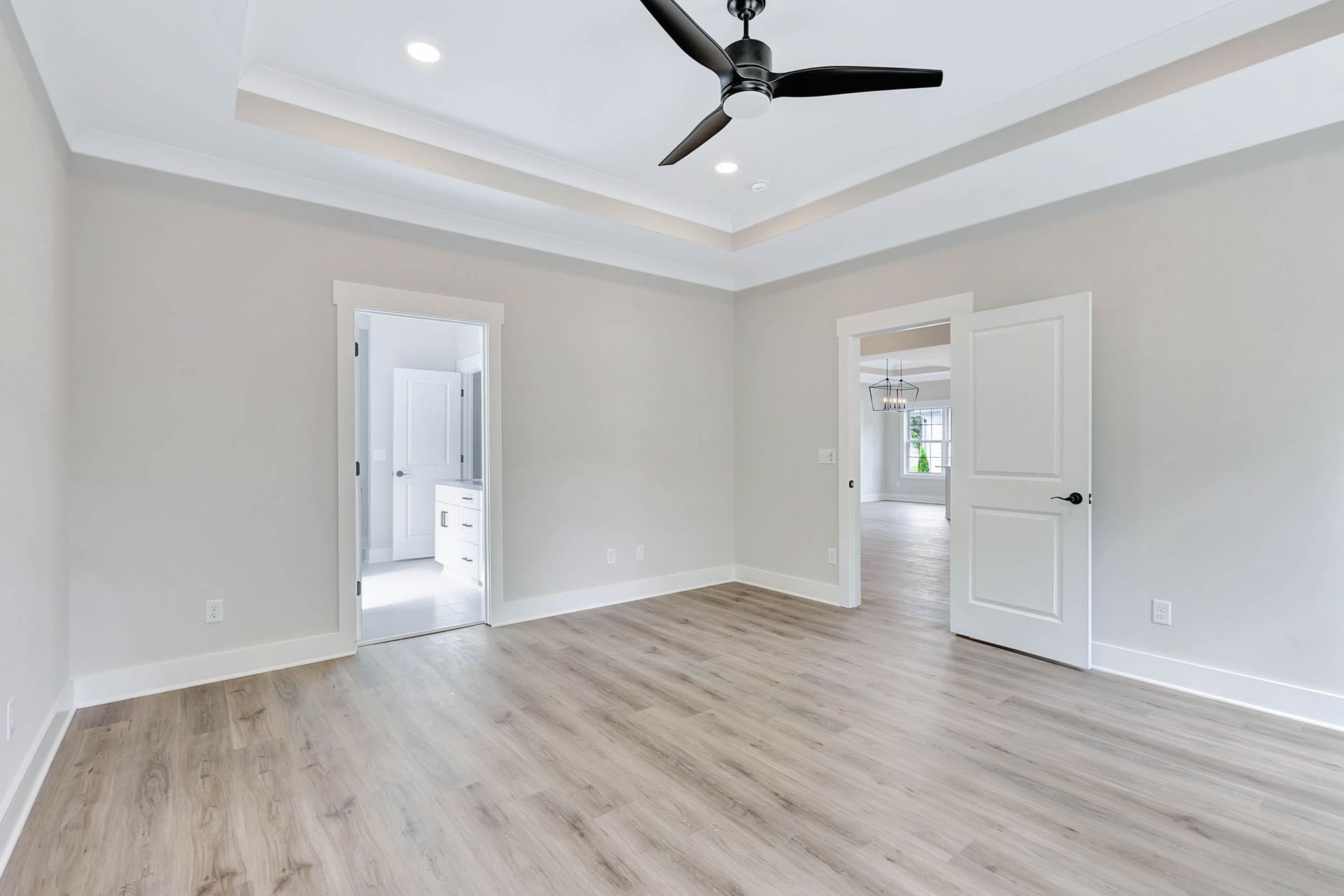 An empty room with hardwood floors and a ceiling fan.