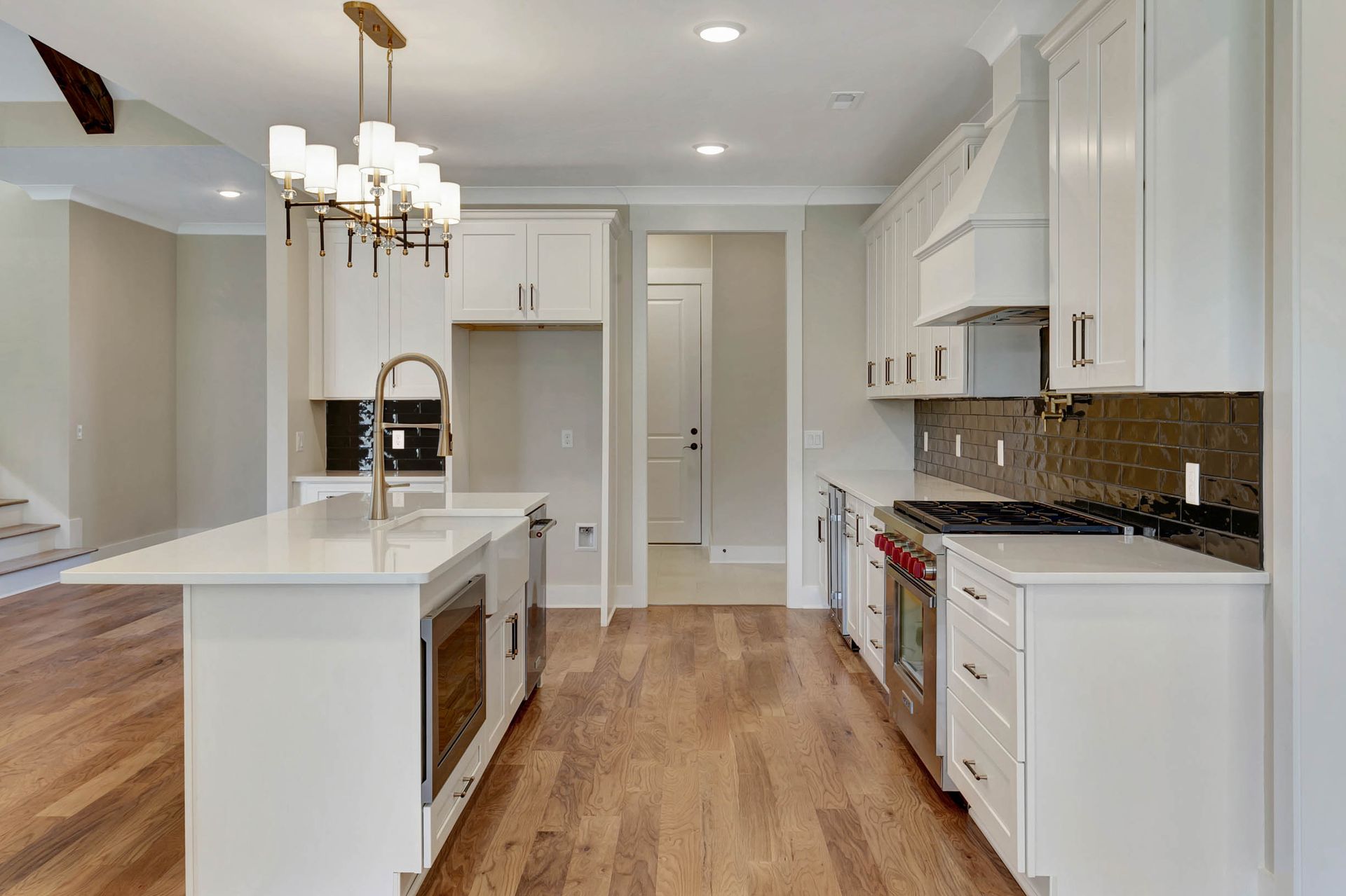 A kitchen with white cabinets , stainless steel appliances , and hardwood floors.