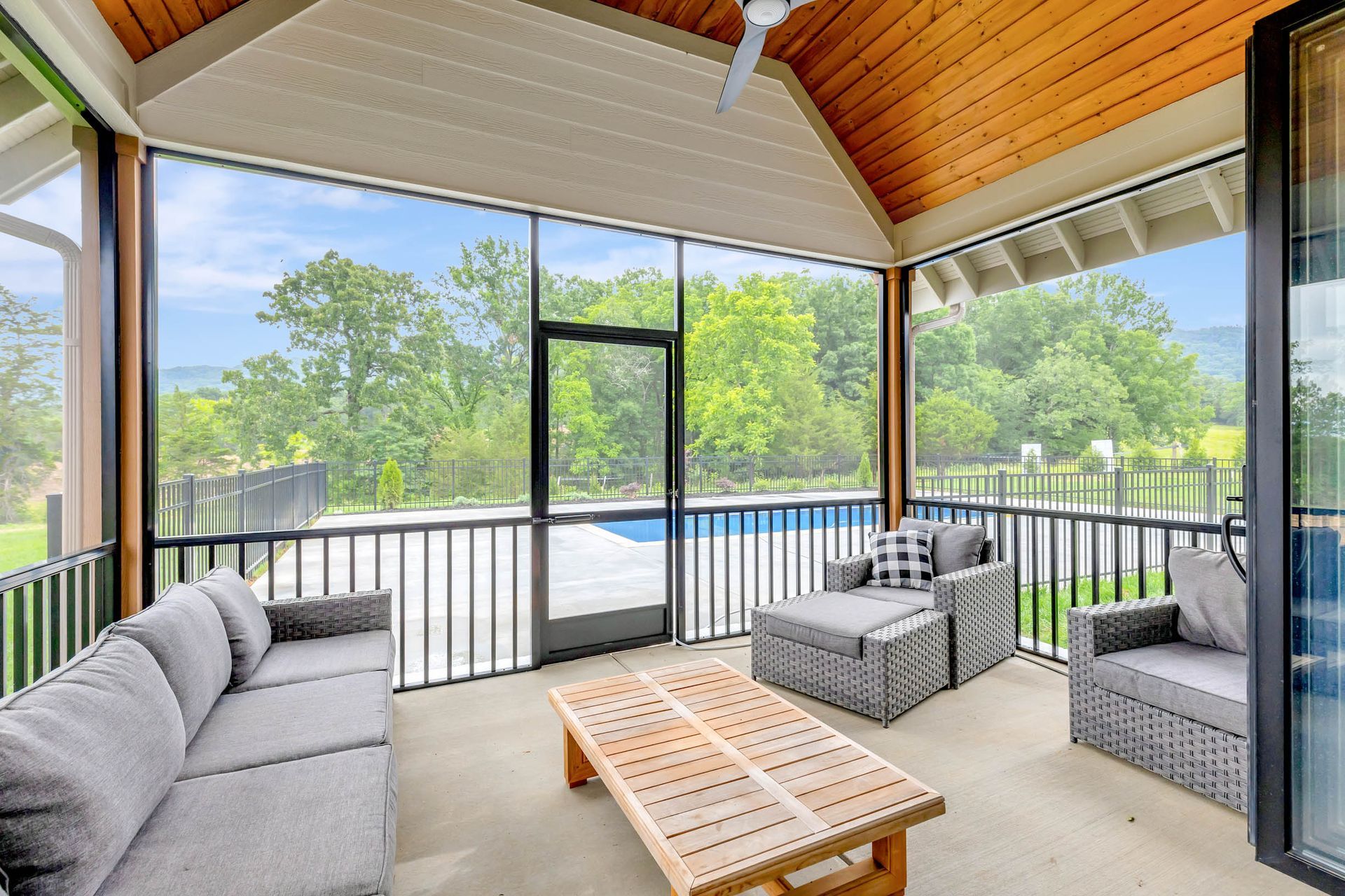 A screened in porch with a couch and chairs and a table