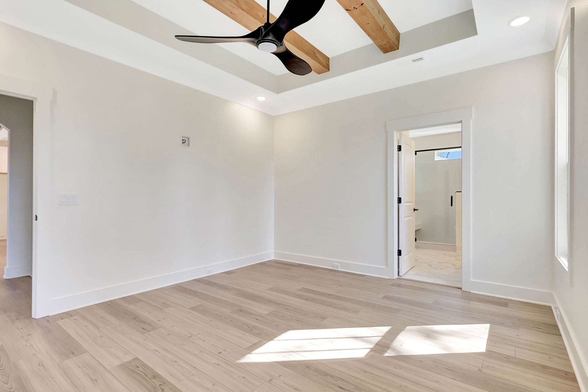 An empty room with a ceiling fan and wooden beams.