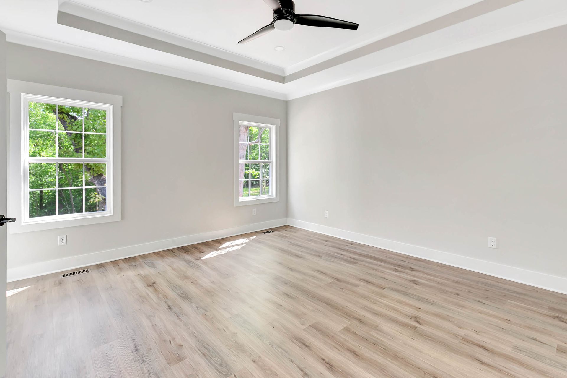An empty room with hardwood floors and a ceiling fan.