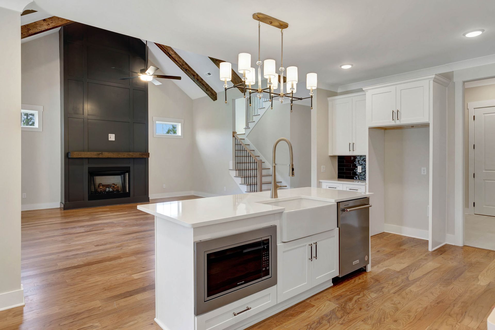 A kitchen with white cabinets , stainless steel appliances , a large island and a fireplace.