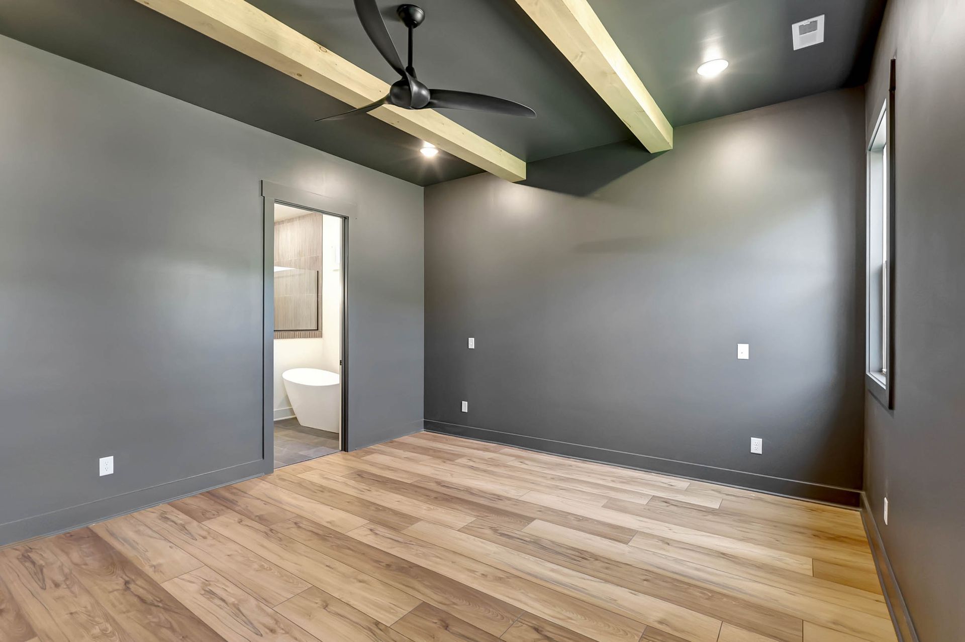 An empty room with a ceiling fan and wooden floors.
