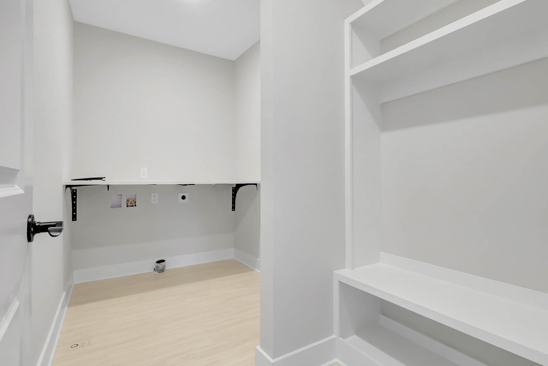 An empty laundry room with a washer and dryer and shelves.