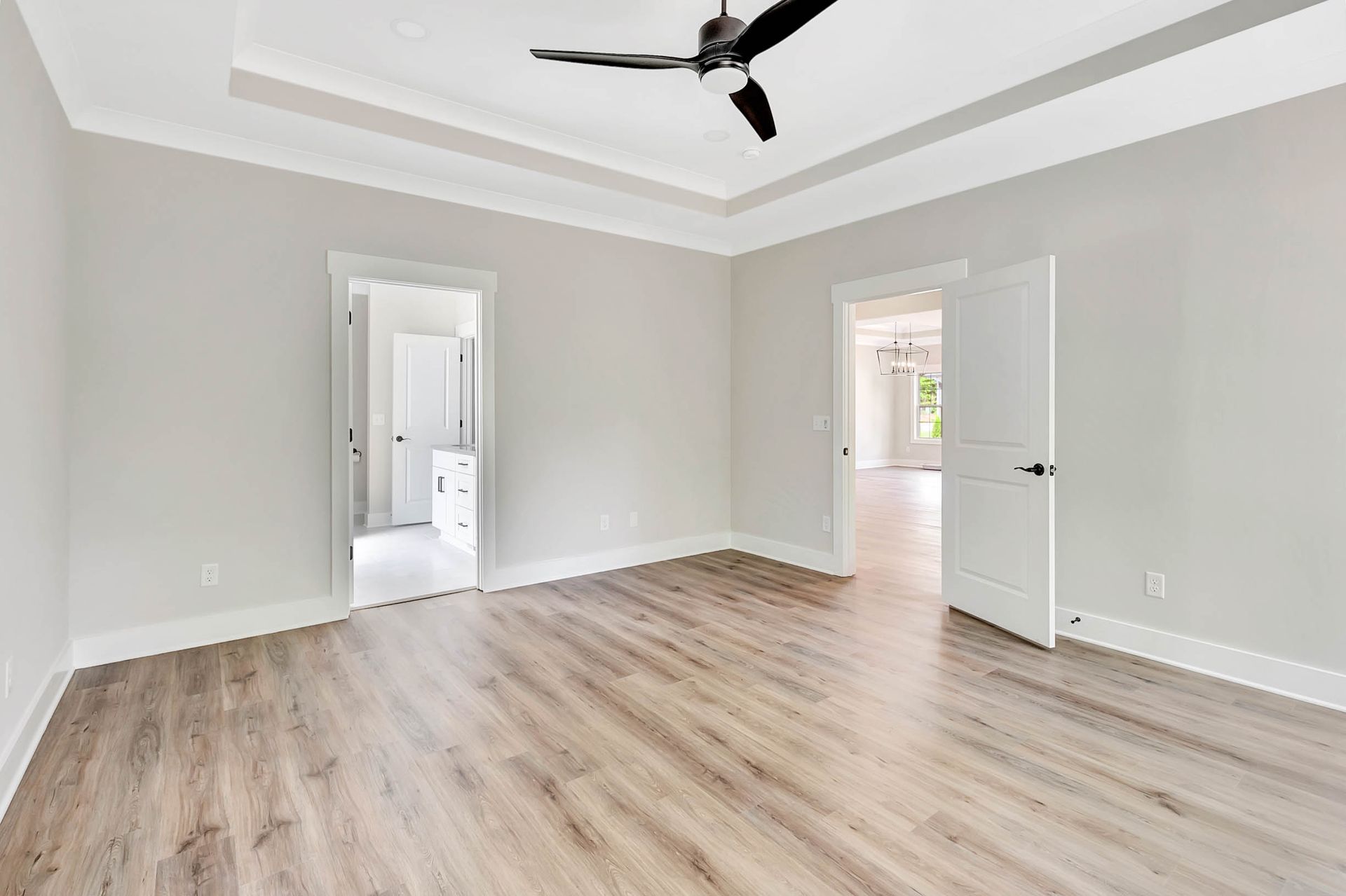 A large empty room with hardwood floors and a ceiling fan.