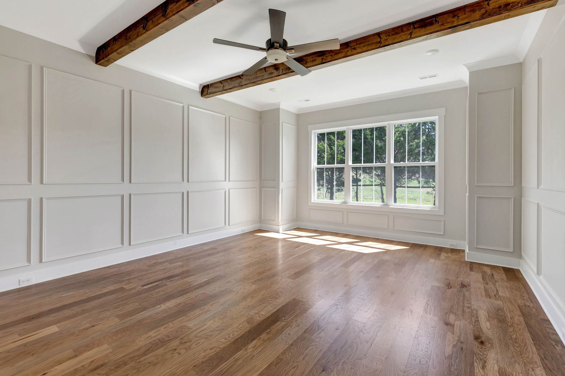 An empty living room with hardwood floors and a ceiling fan.