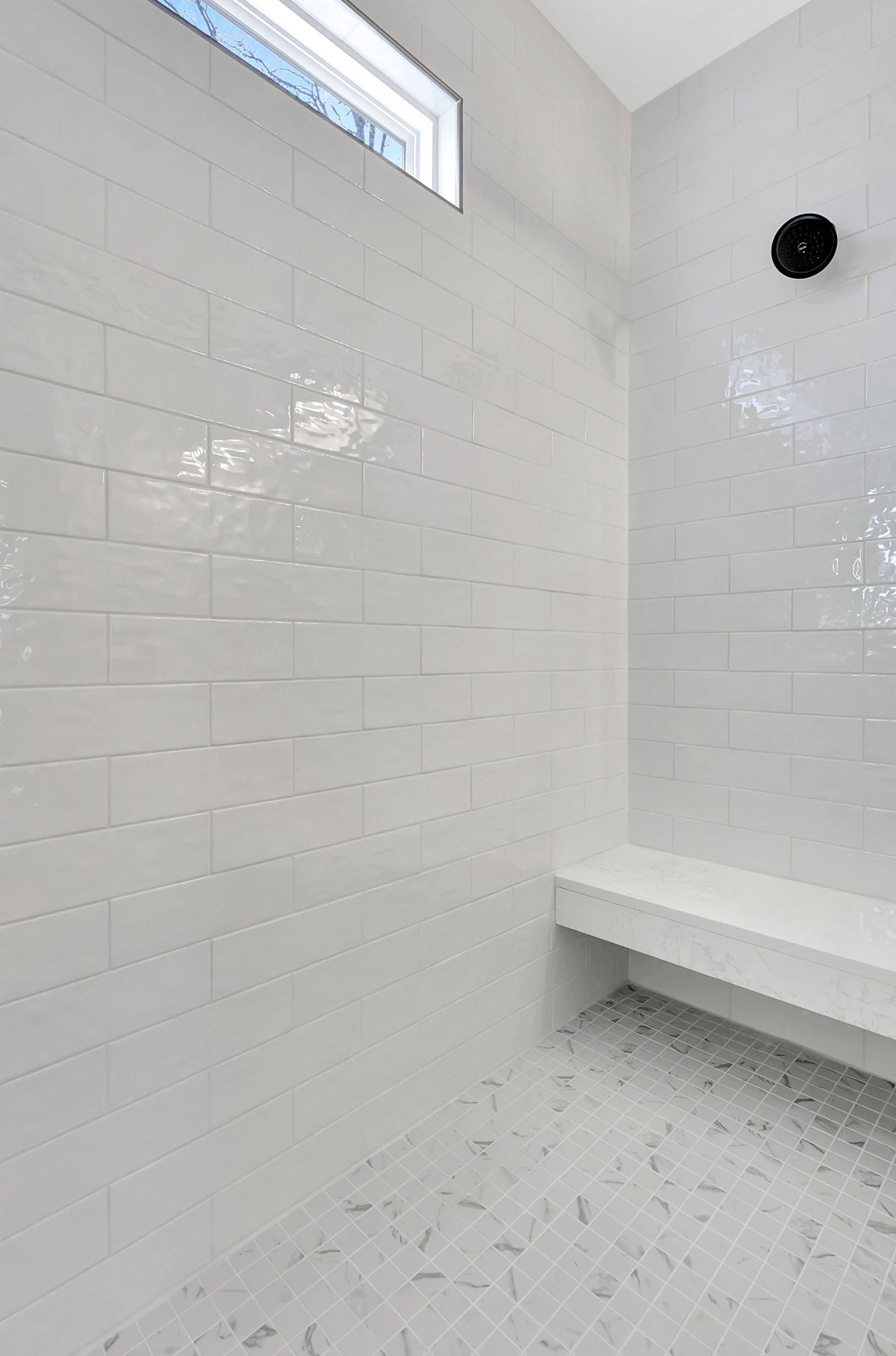 There is a bench in the shower with a window.