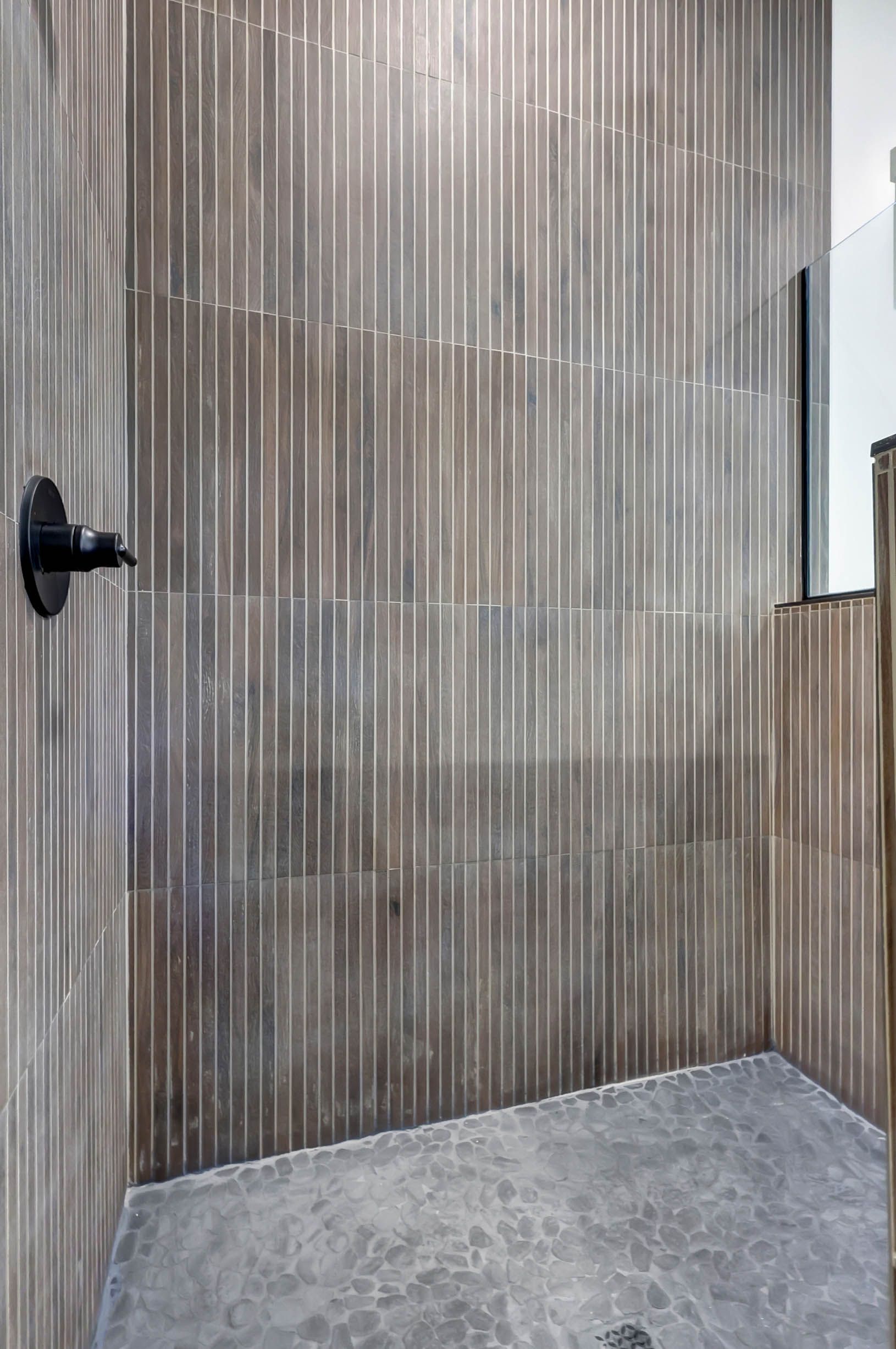 A bathroom with a walk in shower and a tiled wall.