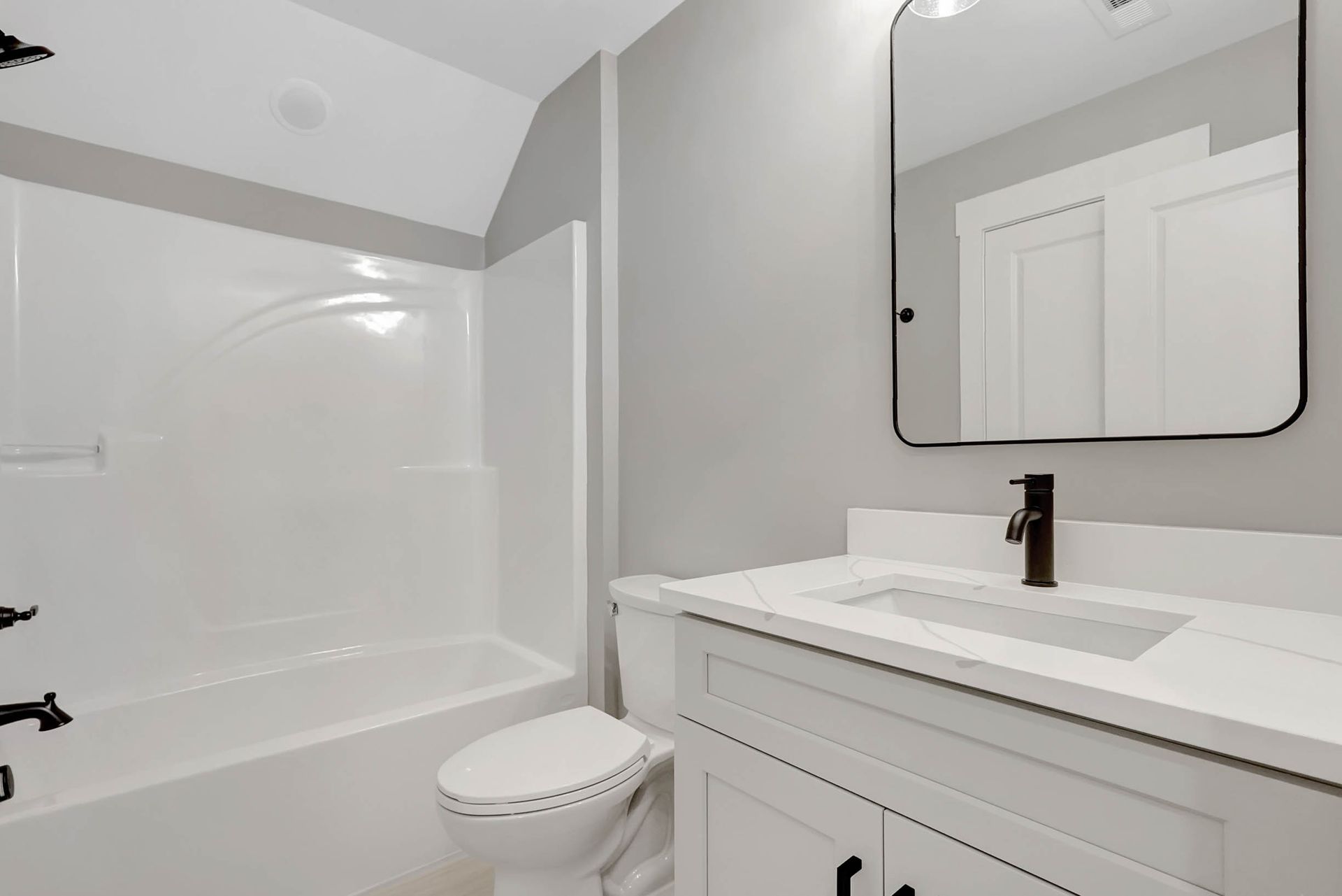 A bathroom with a toilet , sink , bathtub and mirror.
