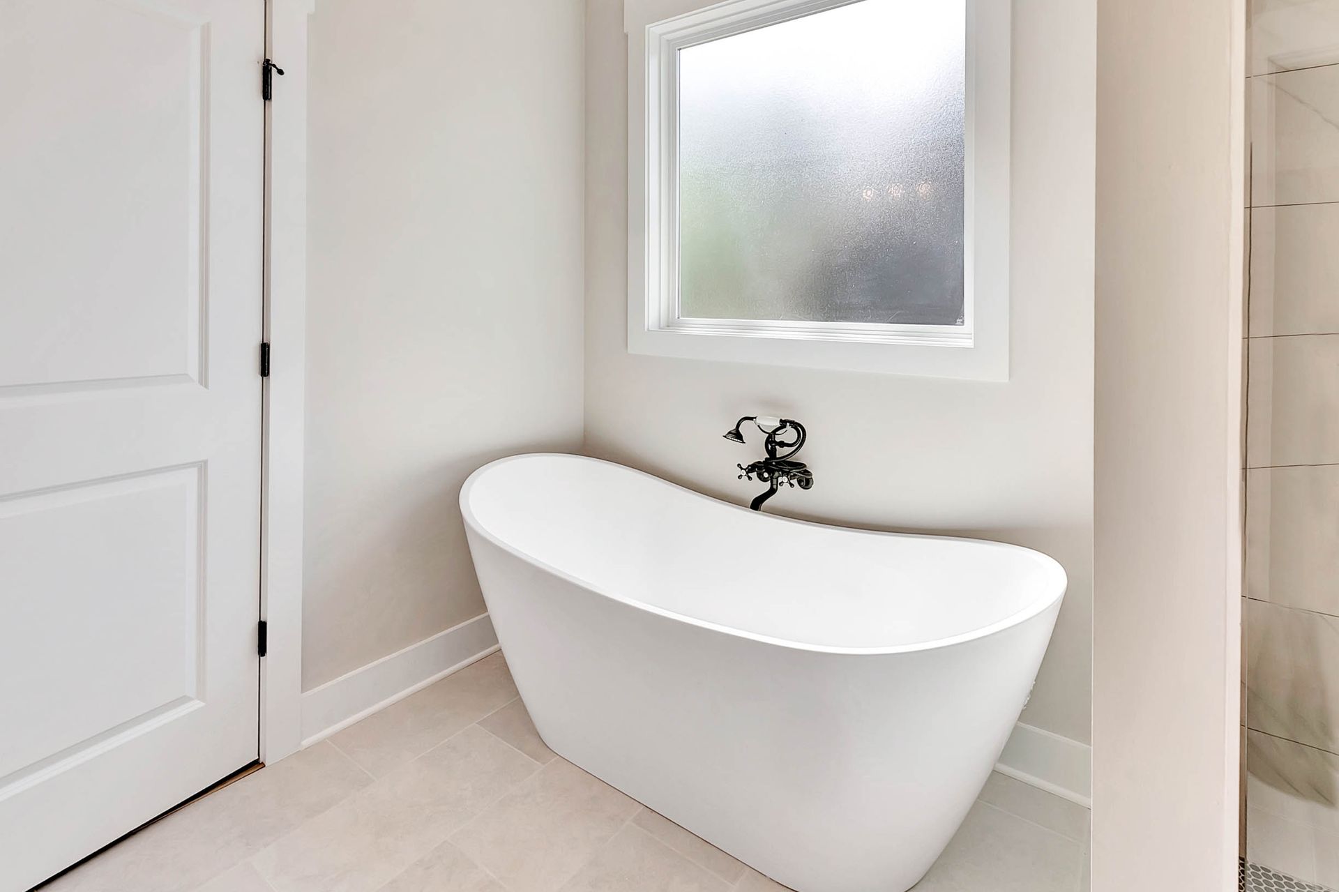 A white bathtub is sitting in a bathroom next to a window.