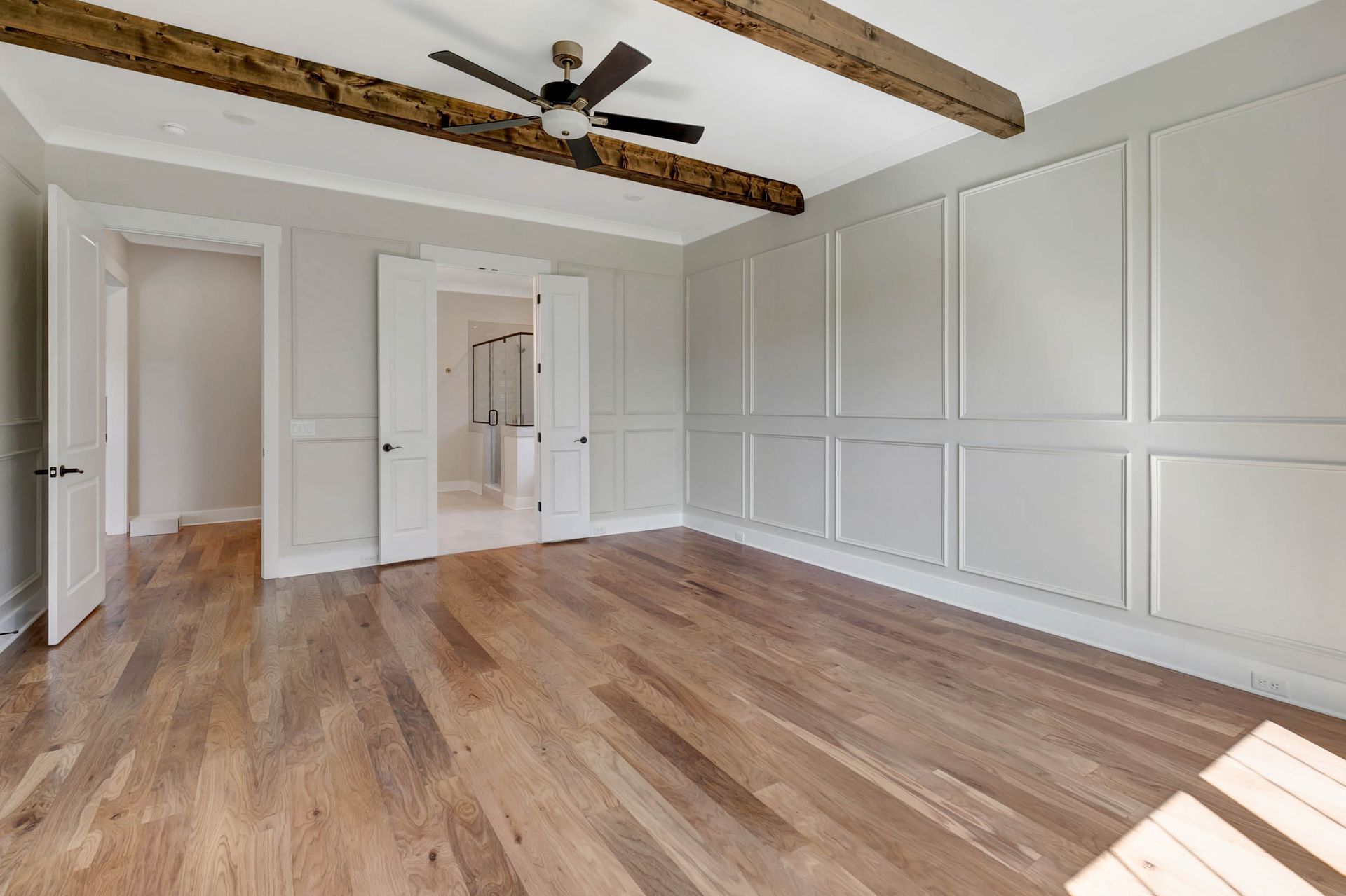 An empty room with hardwood floors and a ceiling fan.