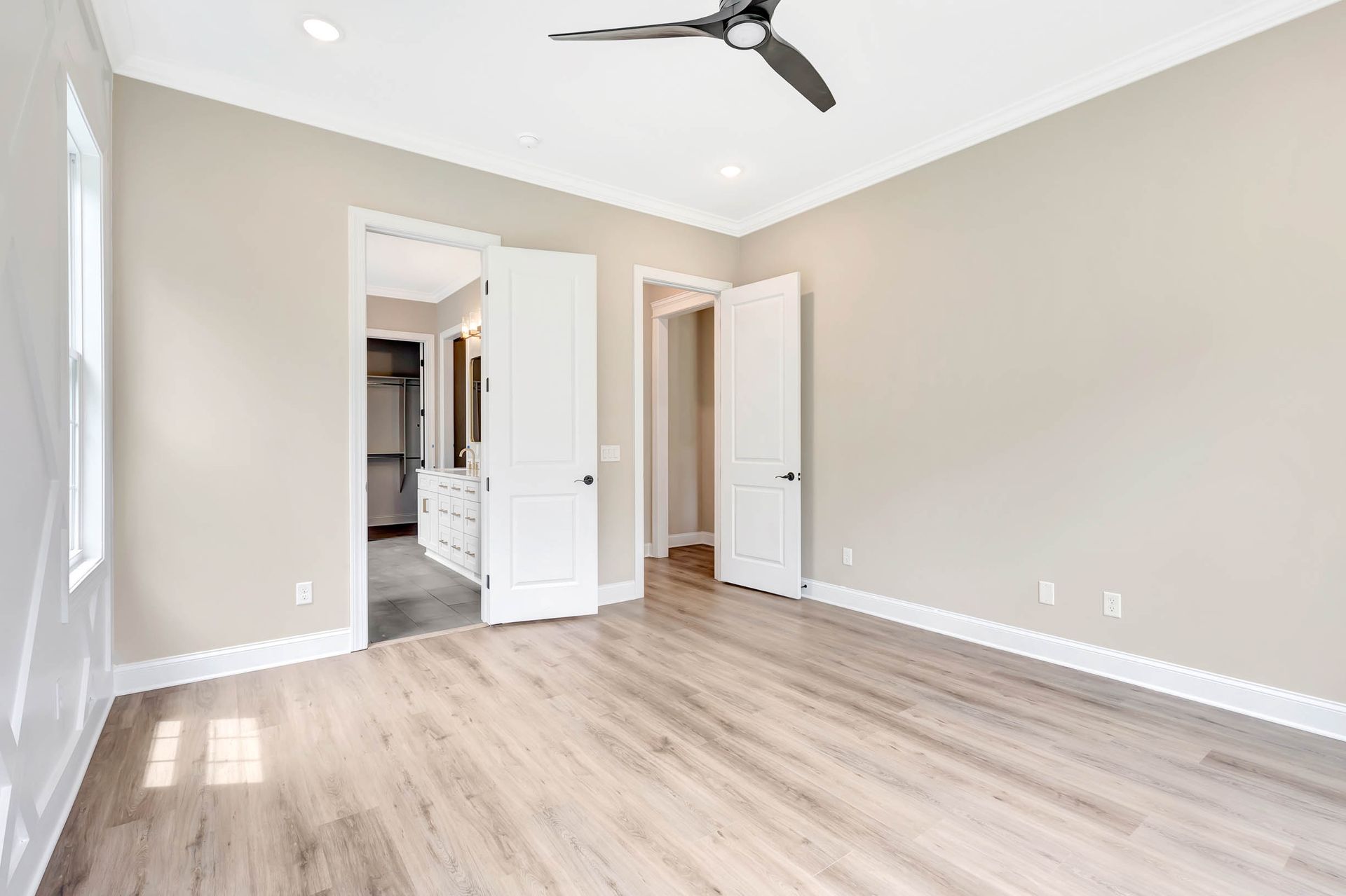An empty bedroom with hardwood floors and a ceiling fan.