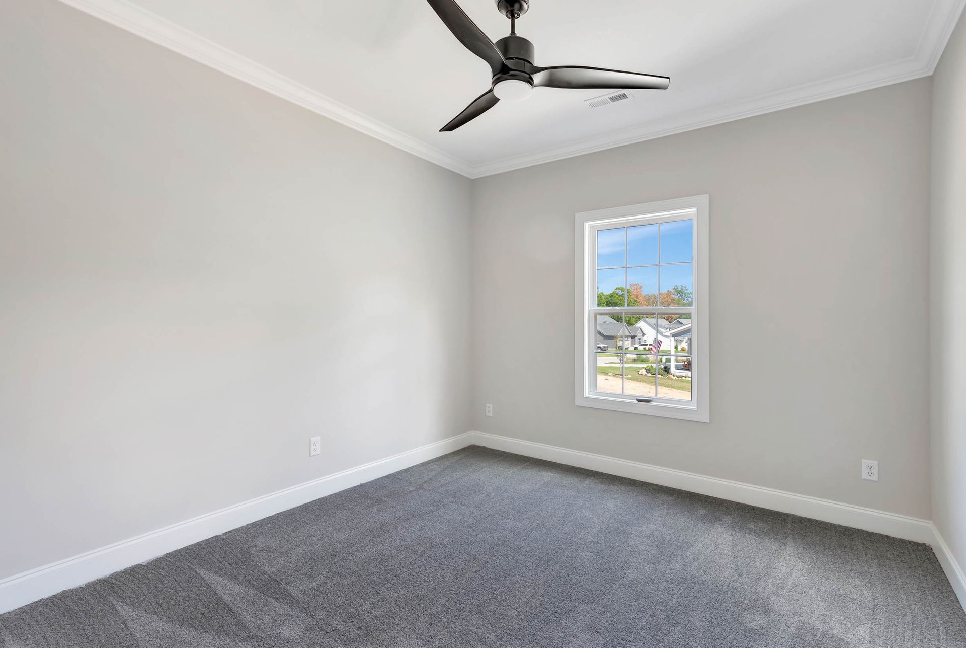 An empty bedroom with a ceiling fan and a window.