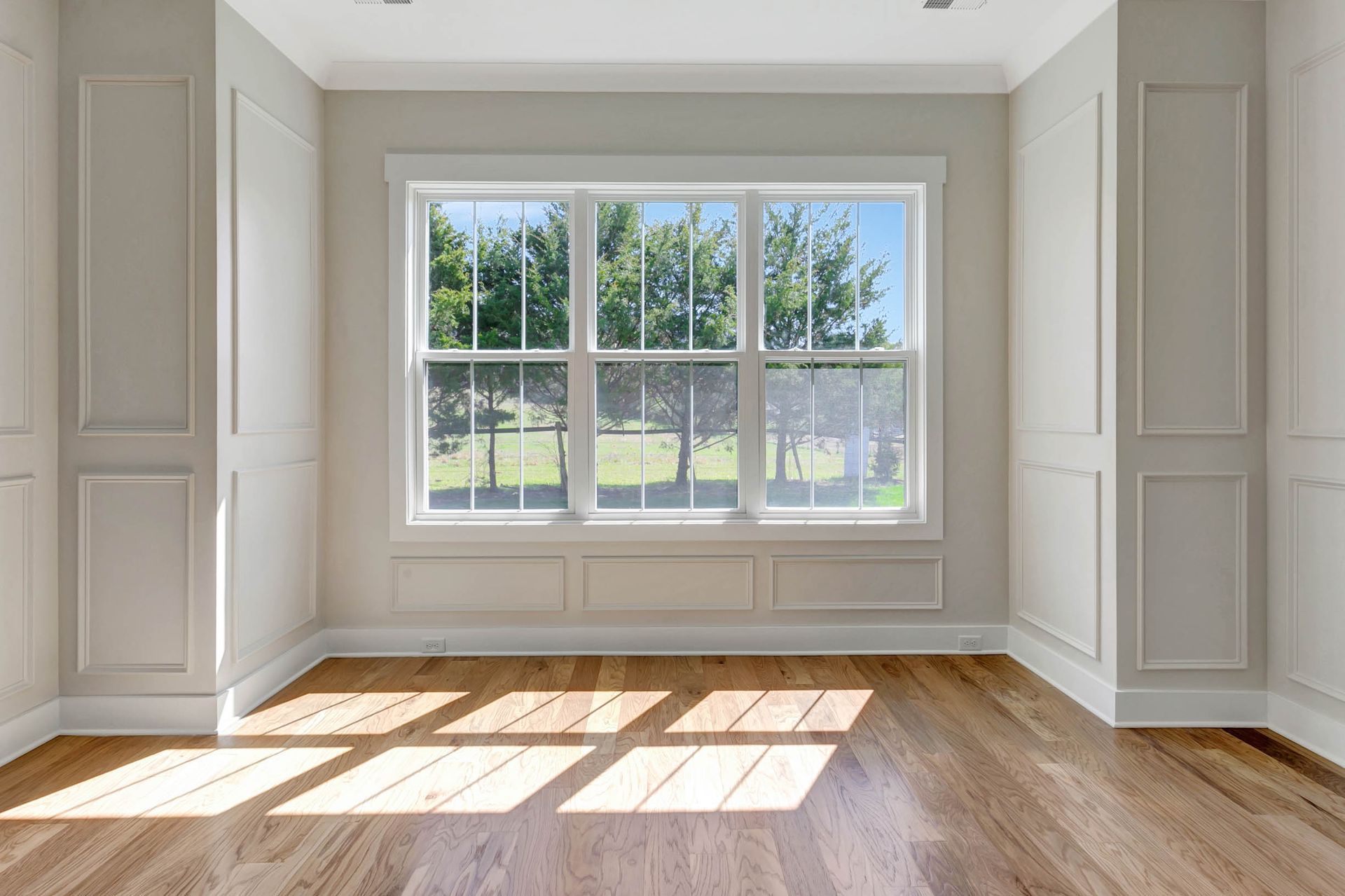 An empty room with hardwood floors and a large window.