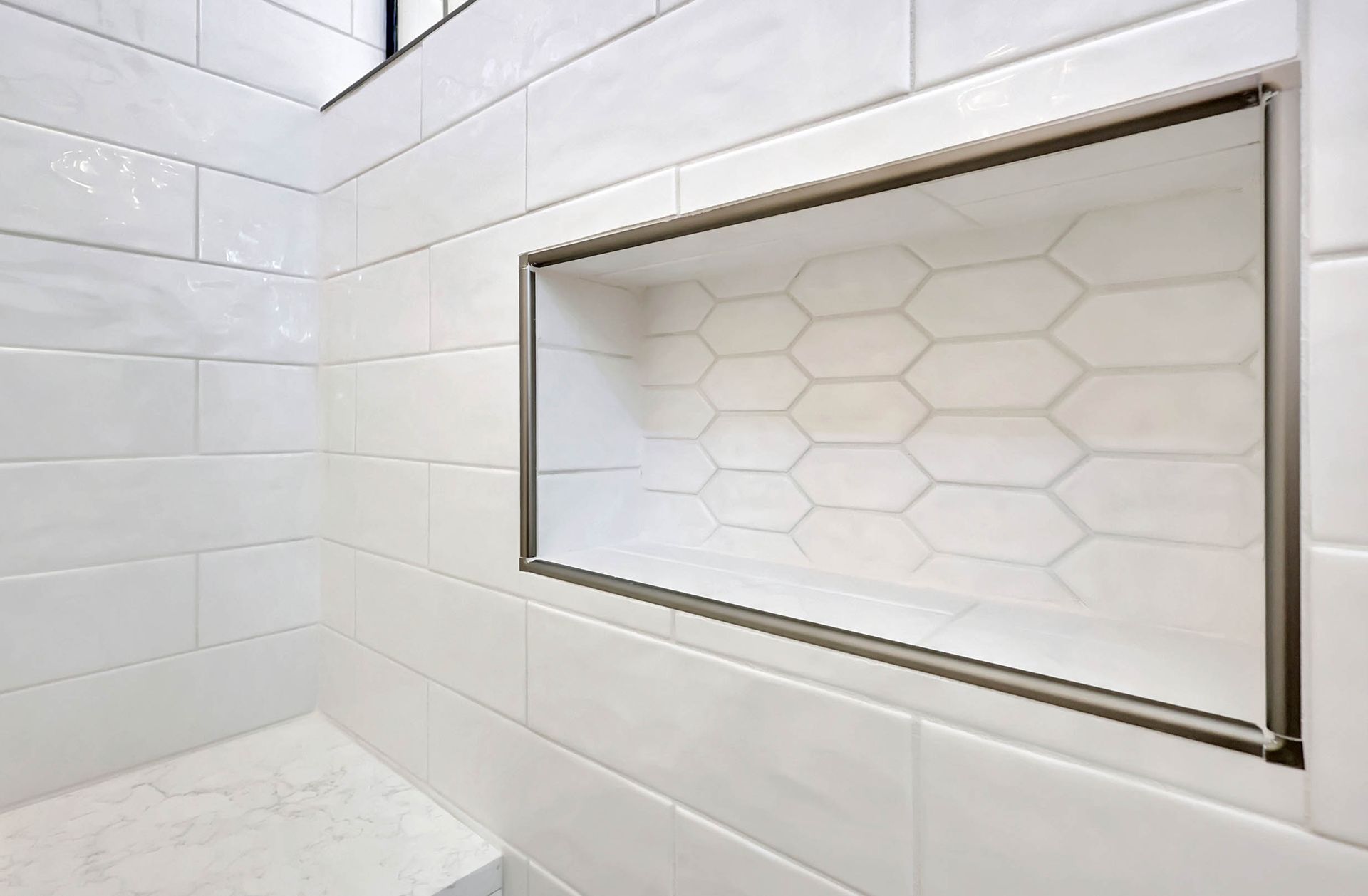 A bathroom with white tiles and a shower niche.