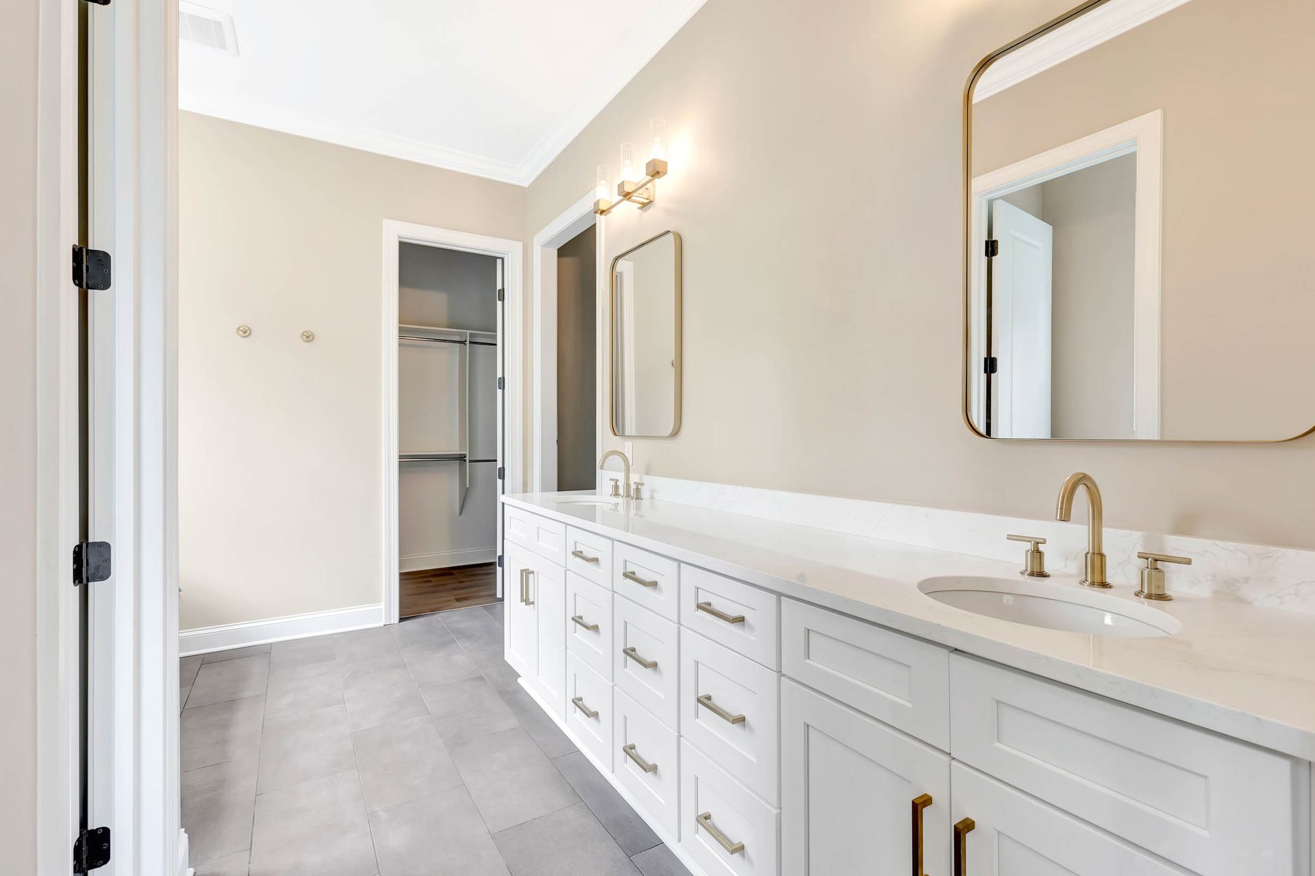 A bathroom with two sinks , a mirror and a walk in closet.