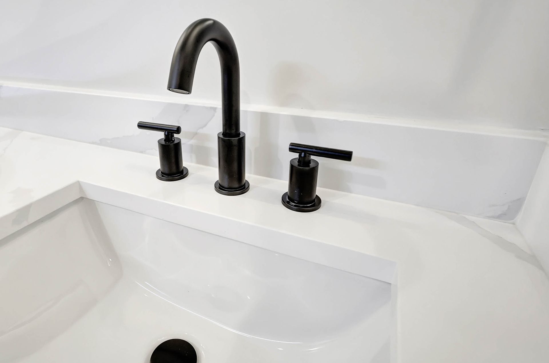 A bathroom sink with a black faucet and a white counter top.