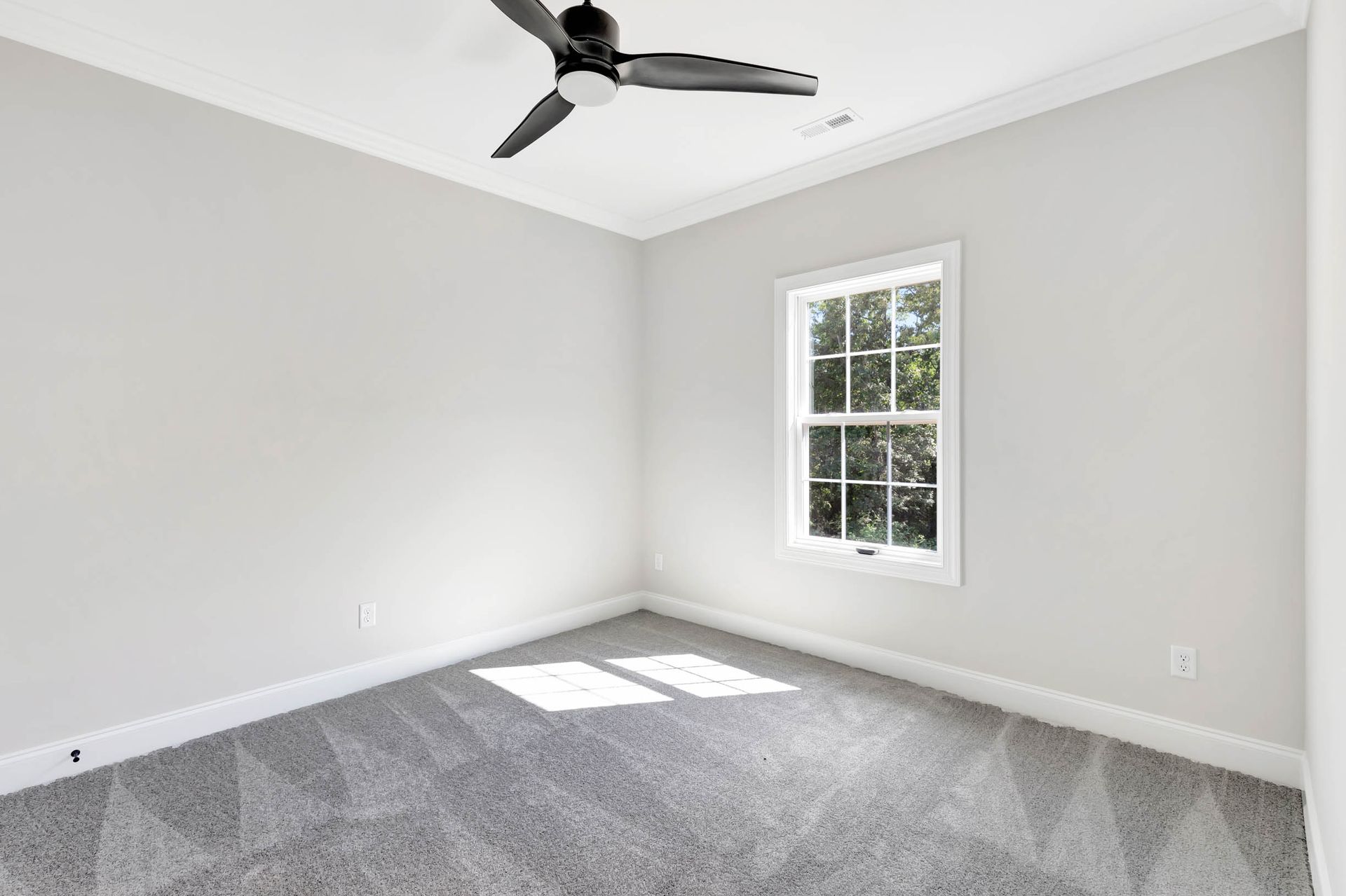 An empty bedroom with a ceiling fan and a window.