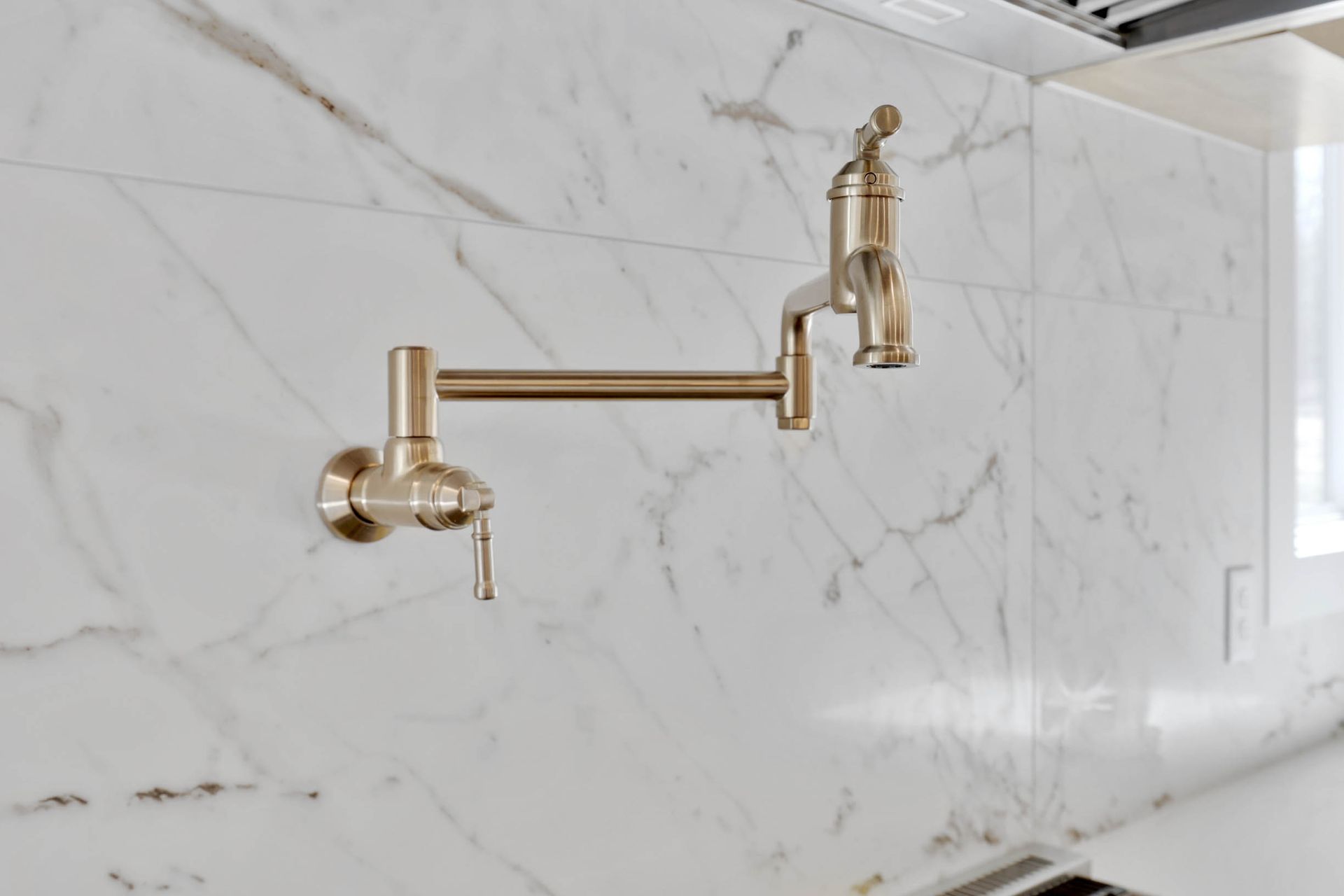A kitchen faucet is hanging on a white marble wall.