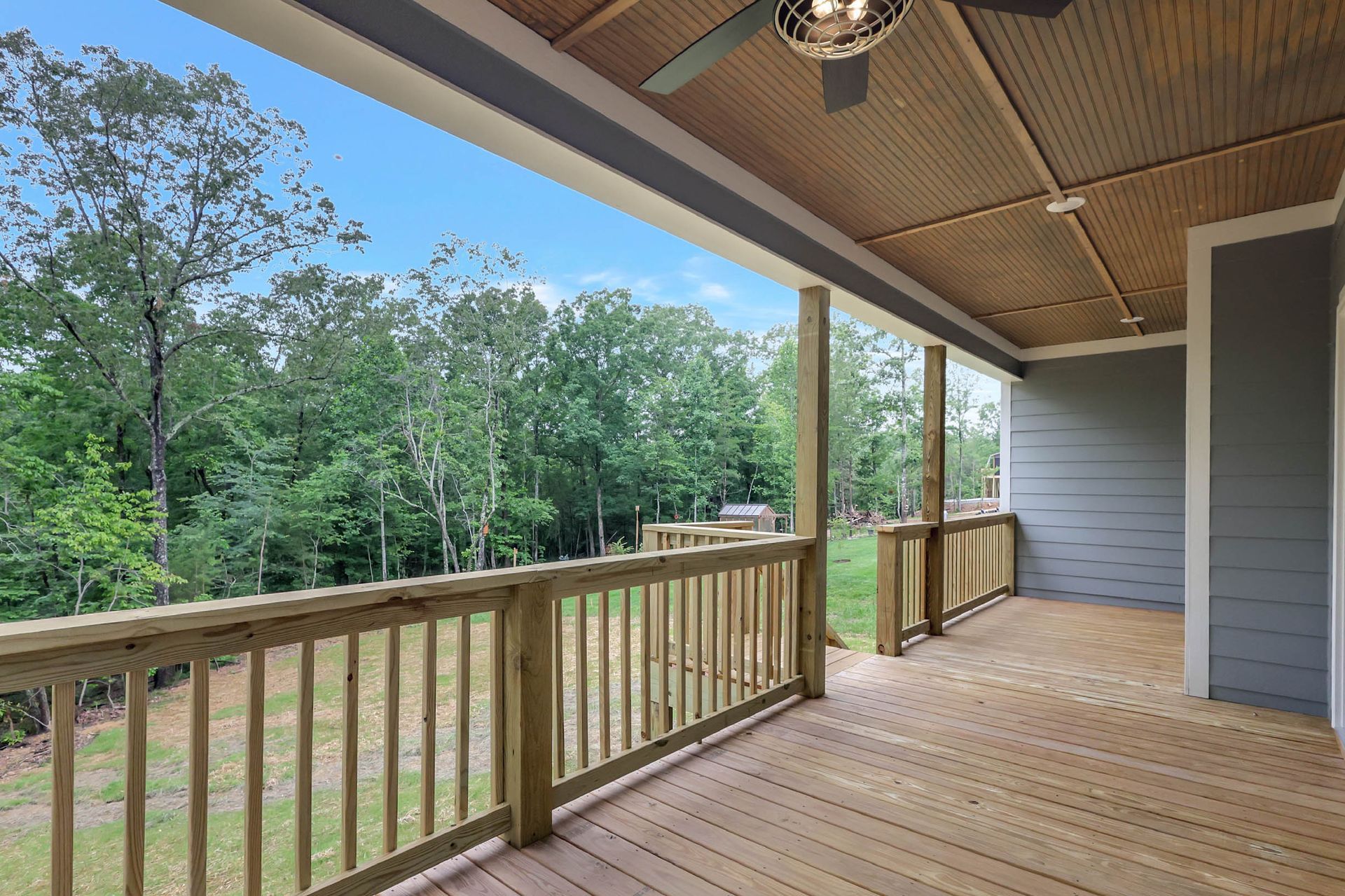 There is a ceiling fan on the porch of a house.