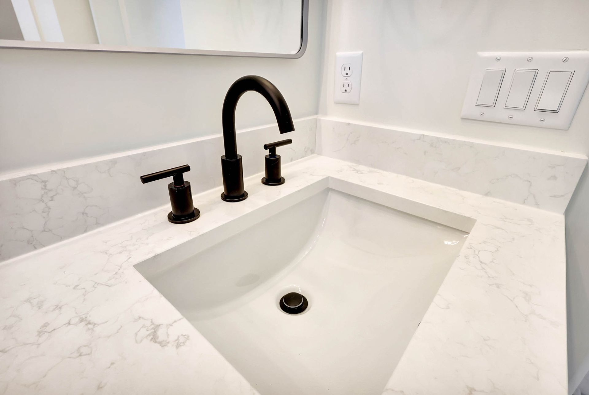 A bathroom sink with a black faucet and a mirror.