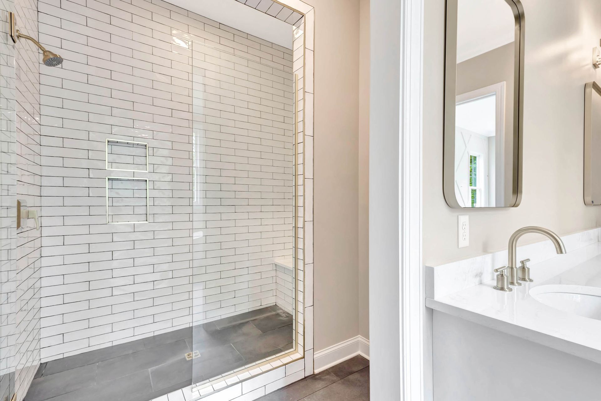 A bathroom with a walk in shower , sink and mirror.