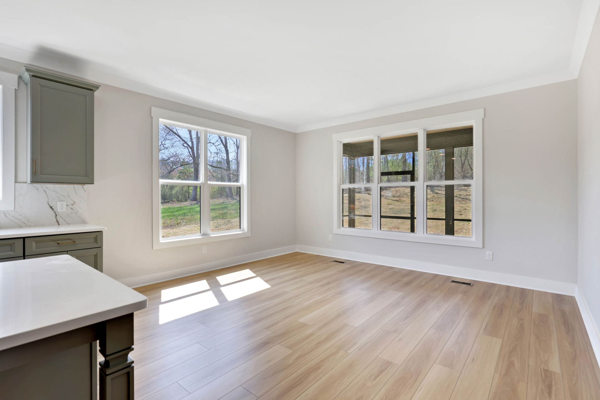 An empty living room with hardwood floors and three windows.