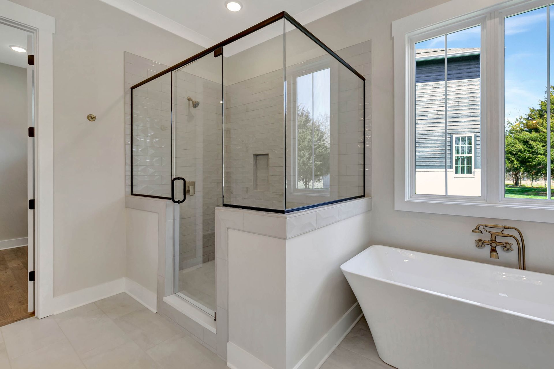 A bathroom with a tub , shower , and window.