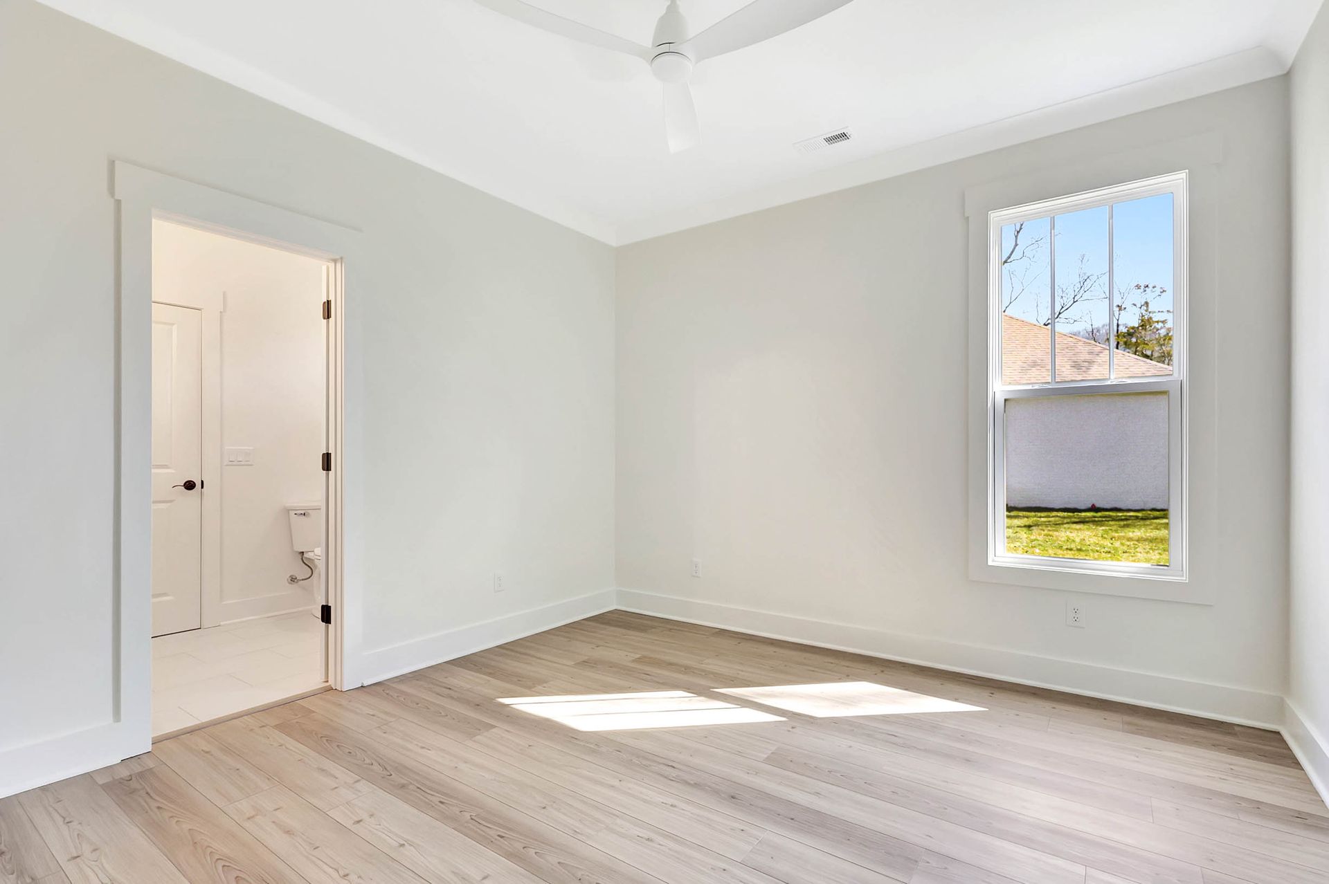 An empty bedroom with hardwood floors and a ceiling fan.