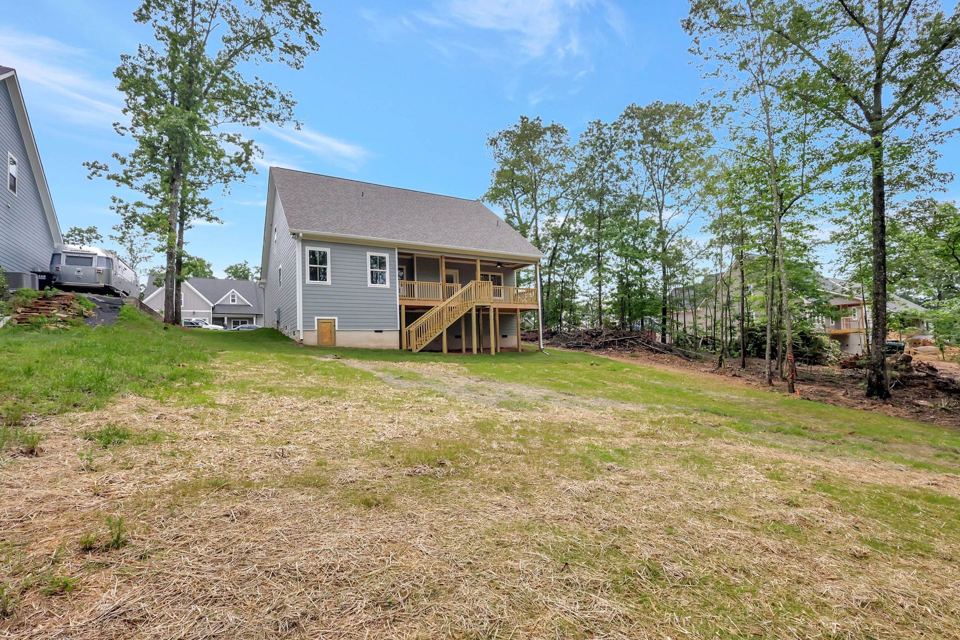 A small house with a deck is sitting on top of a lush green field.