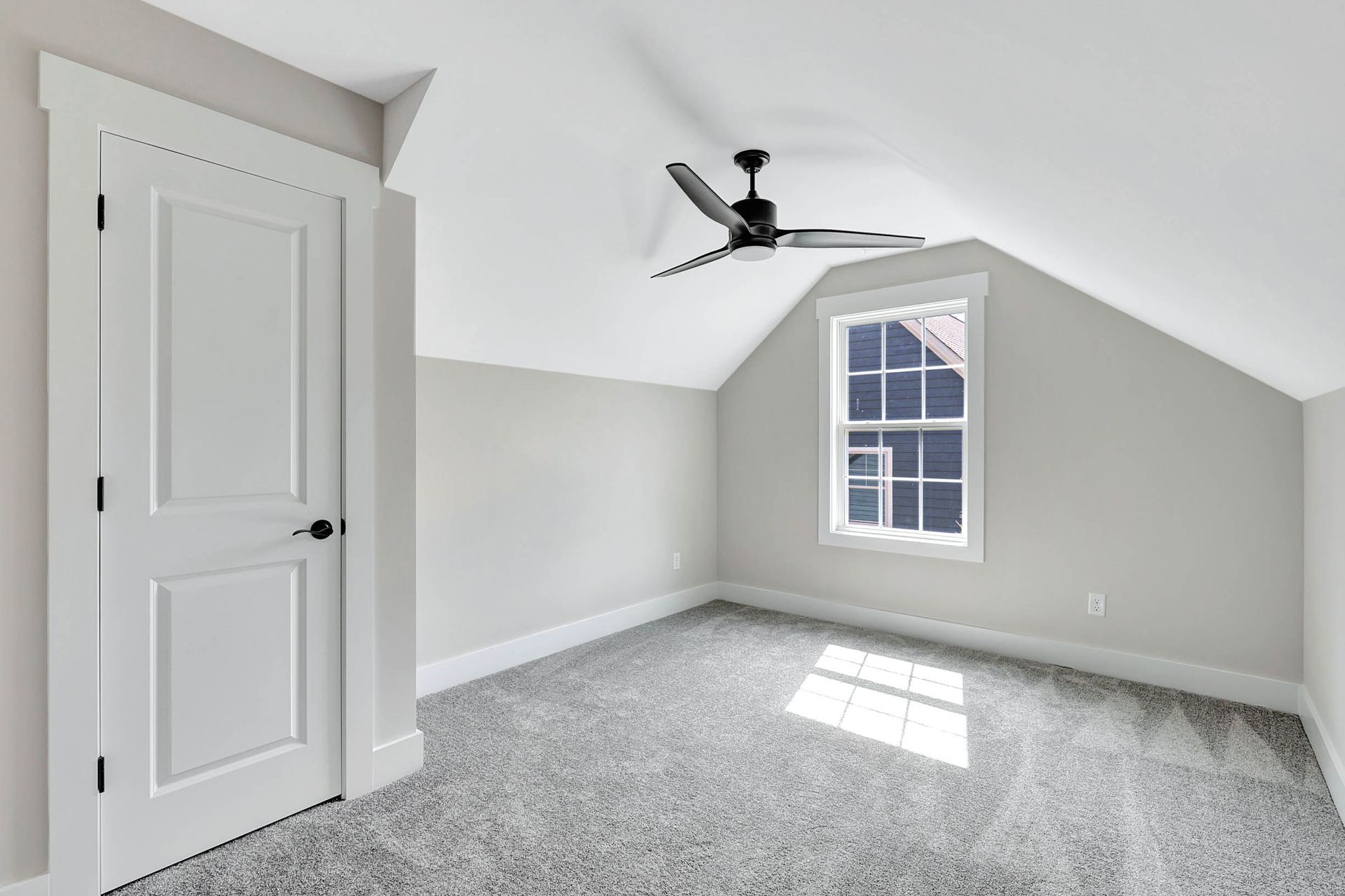 An empty bedroom with a ceiling fan and a window.