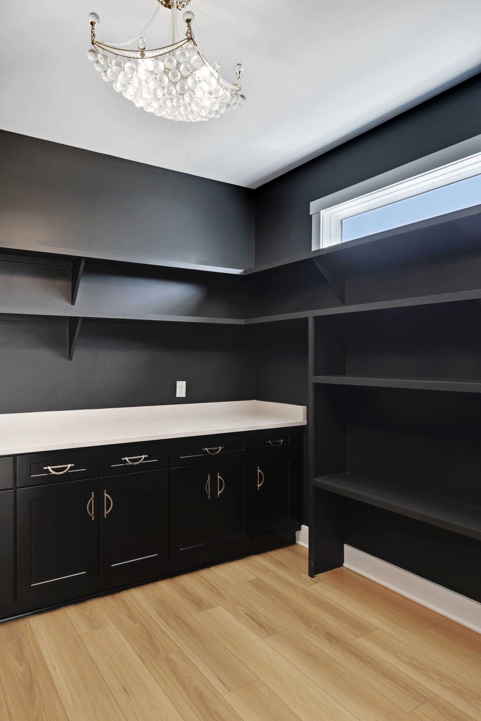 A kitchen with black cabinets and wooden floors.