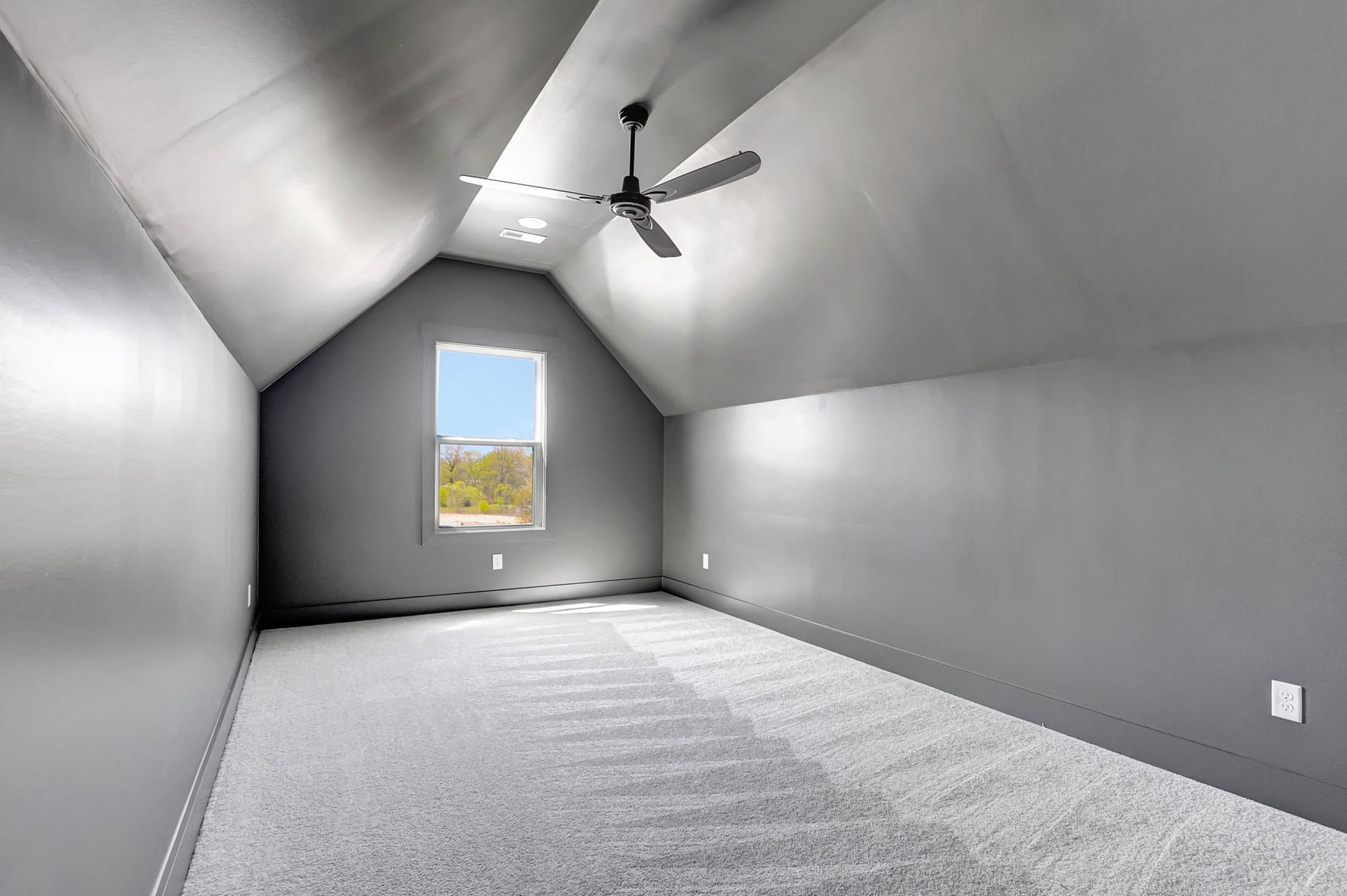 An empty room with a ceiling fan and a window.