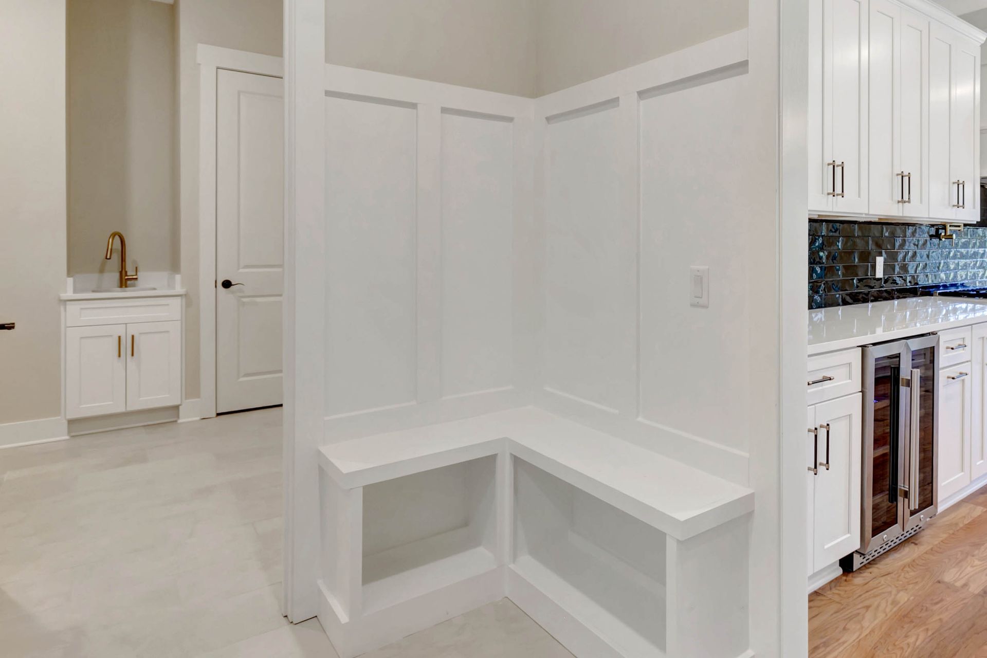 A kitchen with white cabinets , a sink , and a bench.