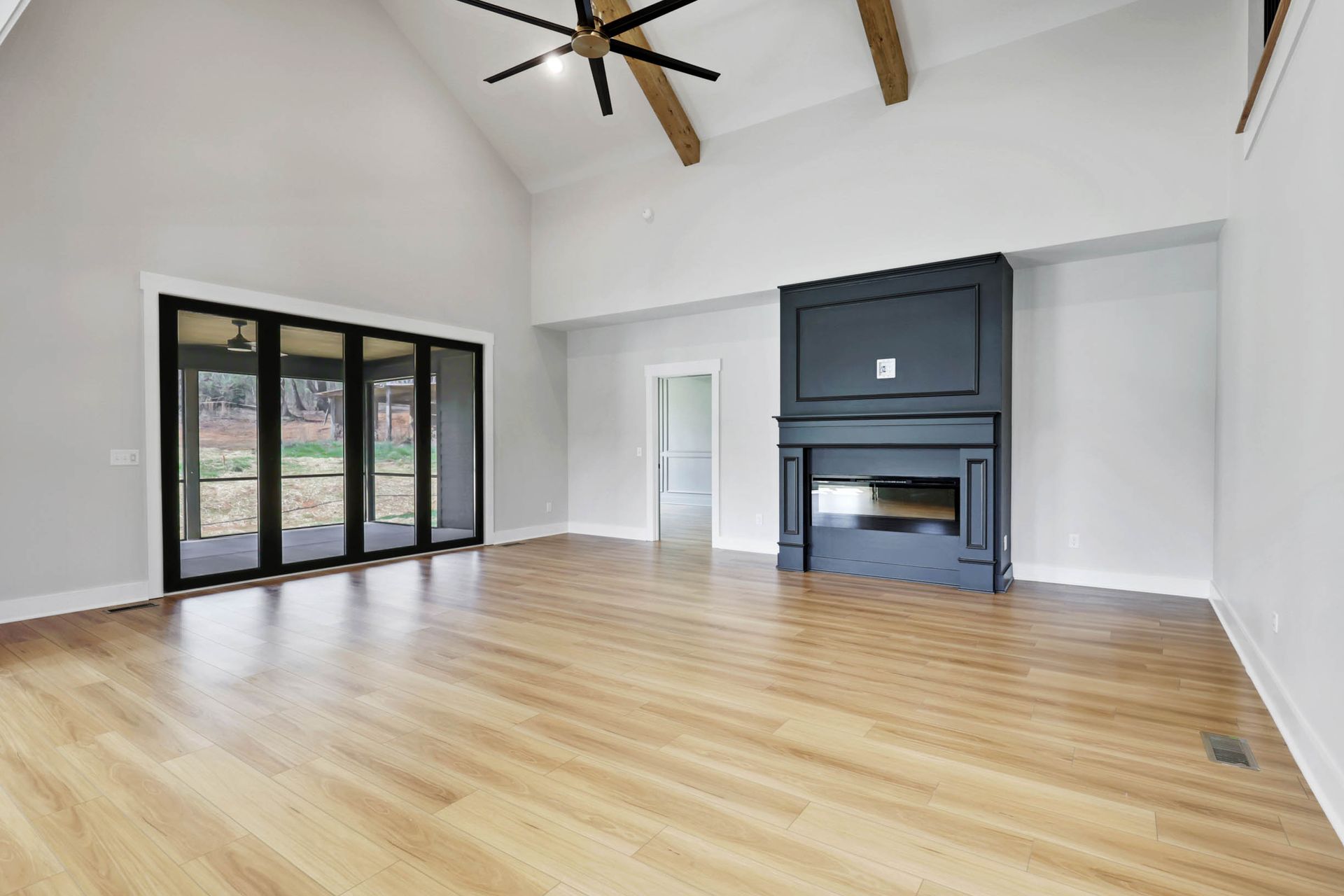 An empty living room with hardwood floors and a fireplace.