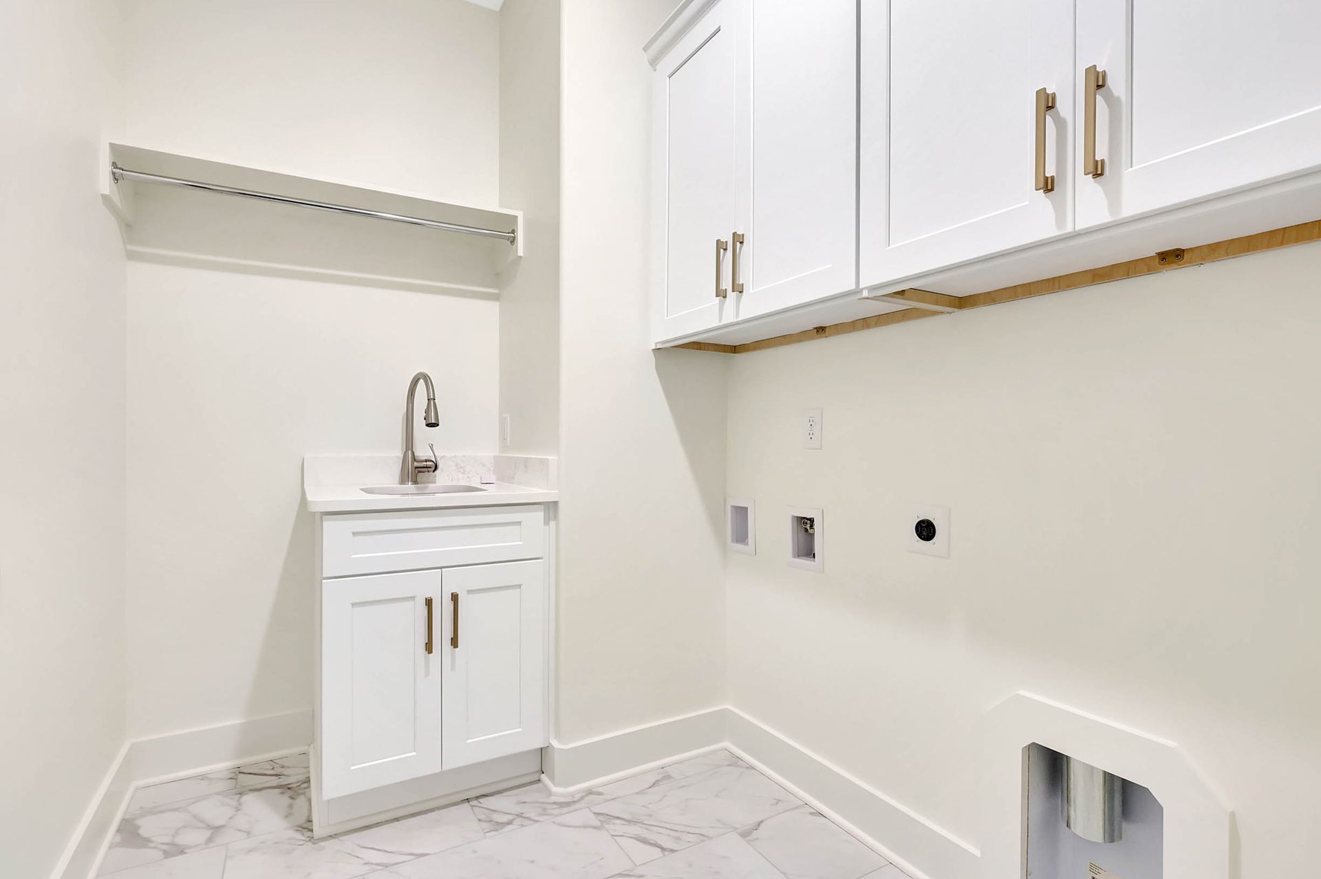 A laundry room with white cabinets and a sink.