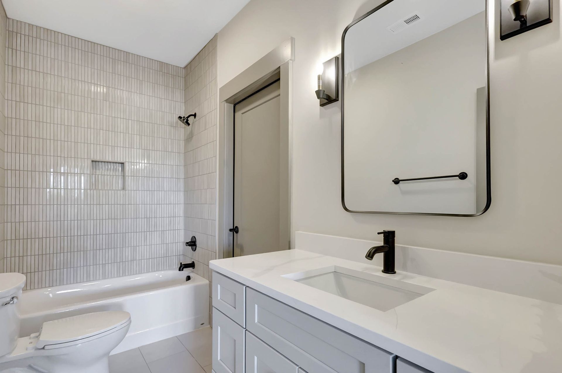 A bathroom with a sink , toilet , bathtub and mirror.