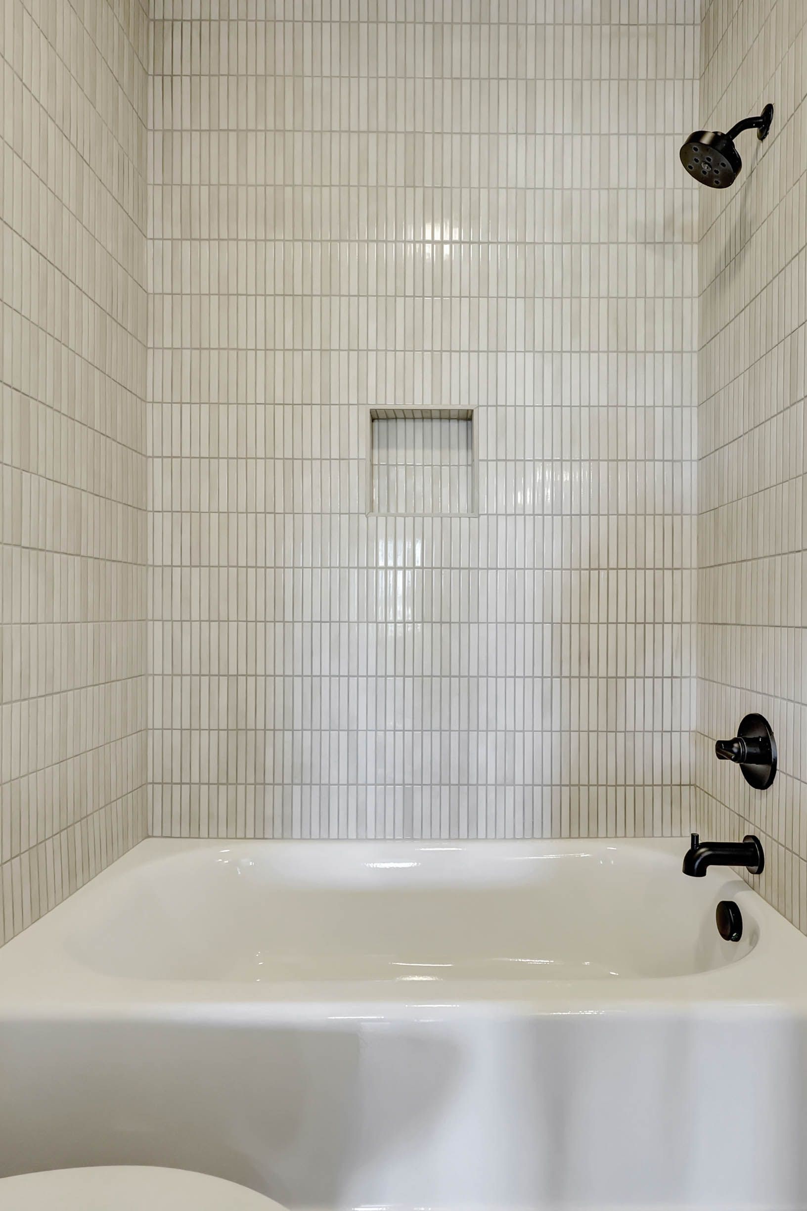 A bathroom with a bathtub , toilet and shower.