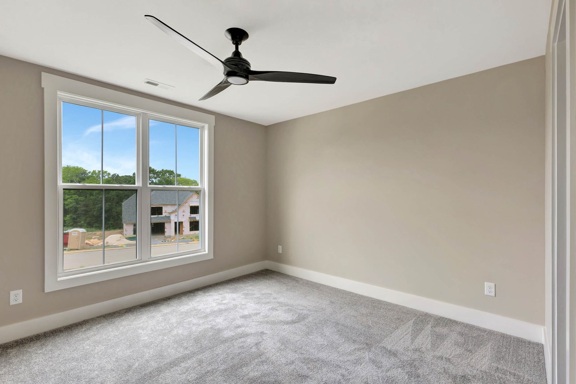 An empty bedroom with a ceiling fan and a large window.