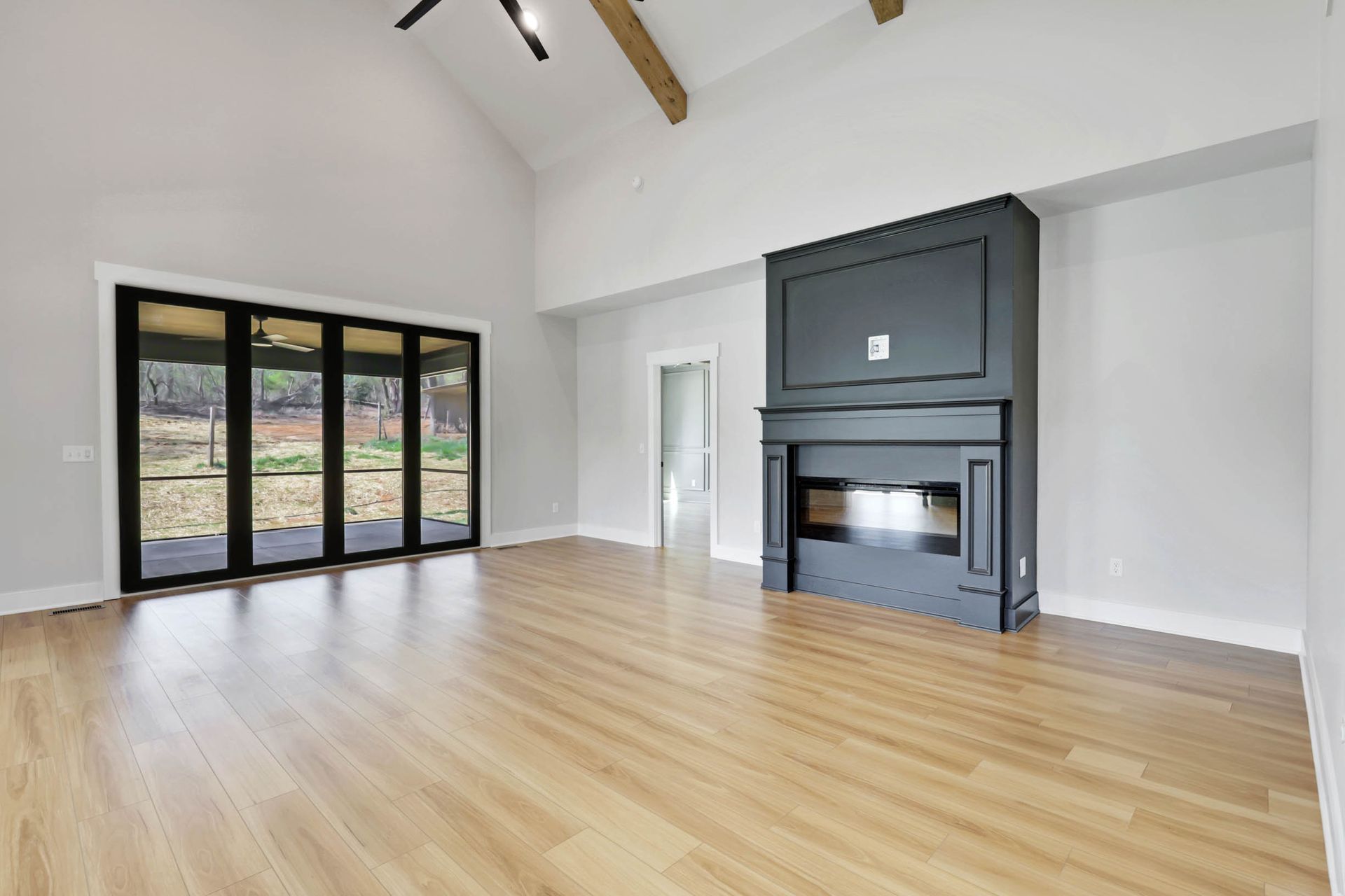 An empty living room with hardwood floors and a fireplace.