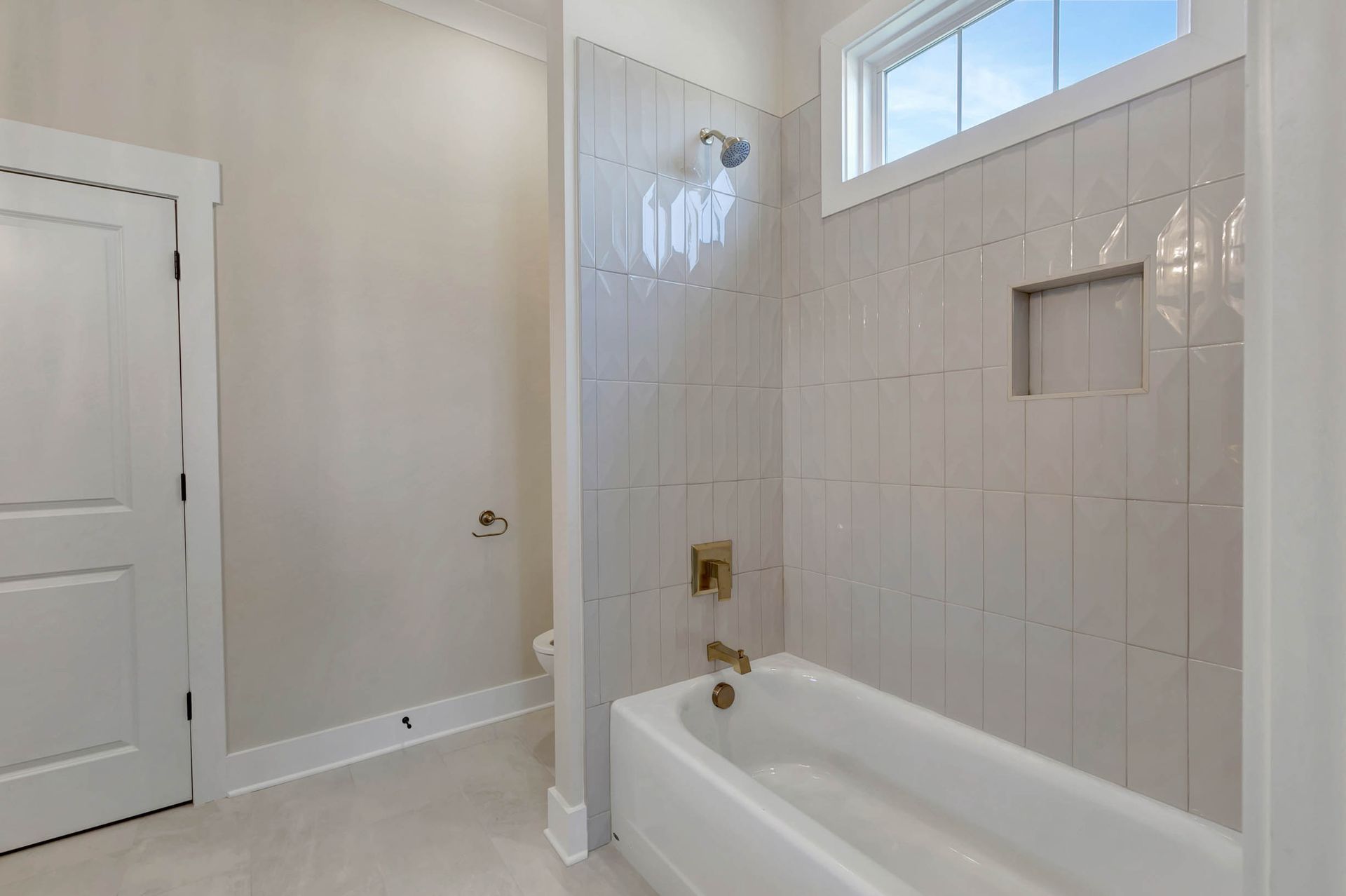 A bathroom with a tub , shower , and window.
