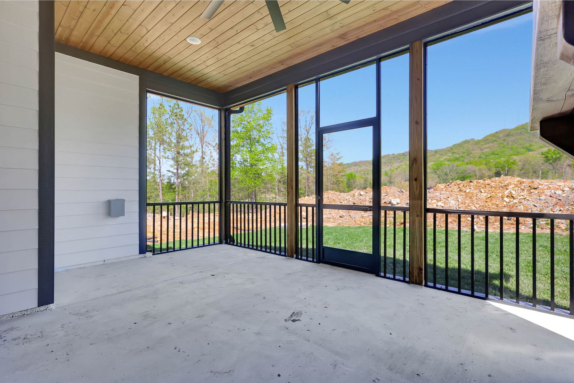 An empty screened in porch with a ceiling fan