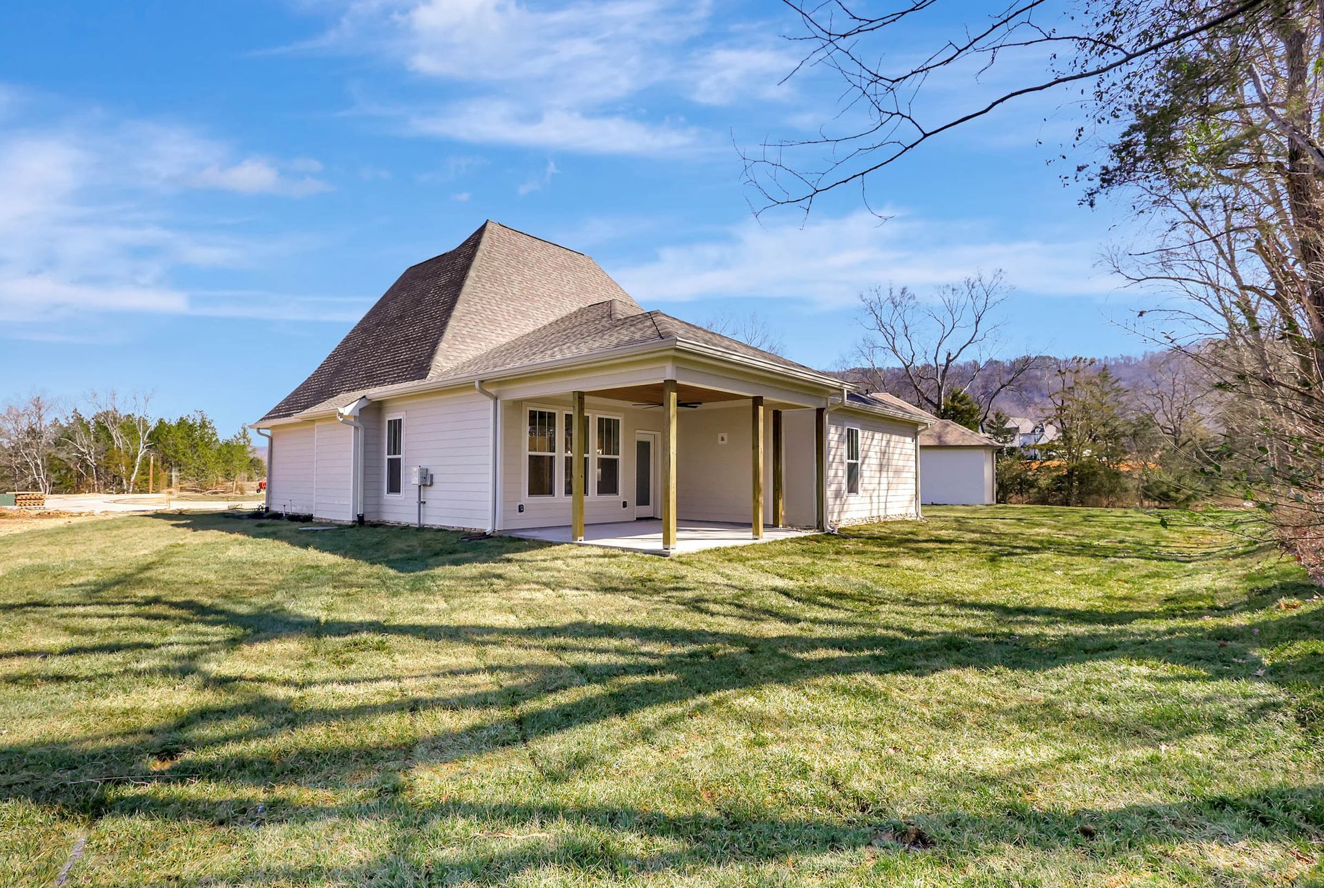 A white house with a porch is sitting in the middle of a lush green field.