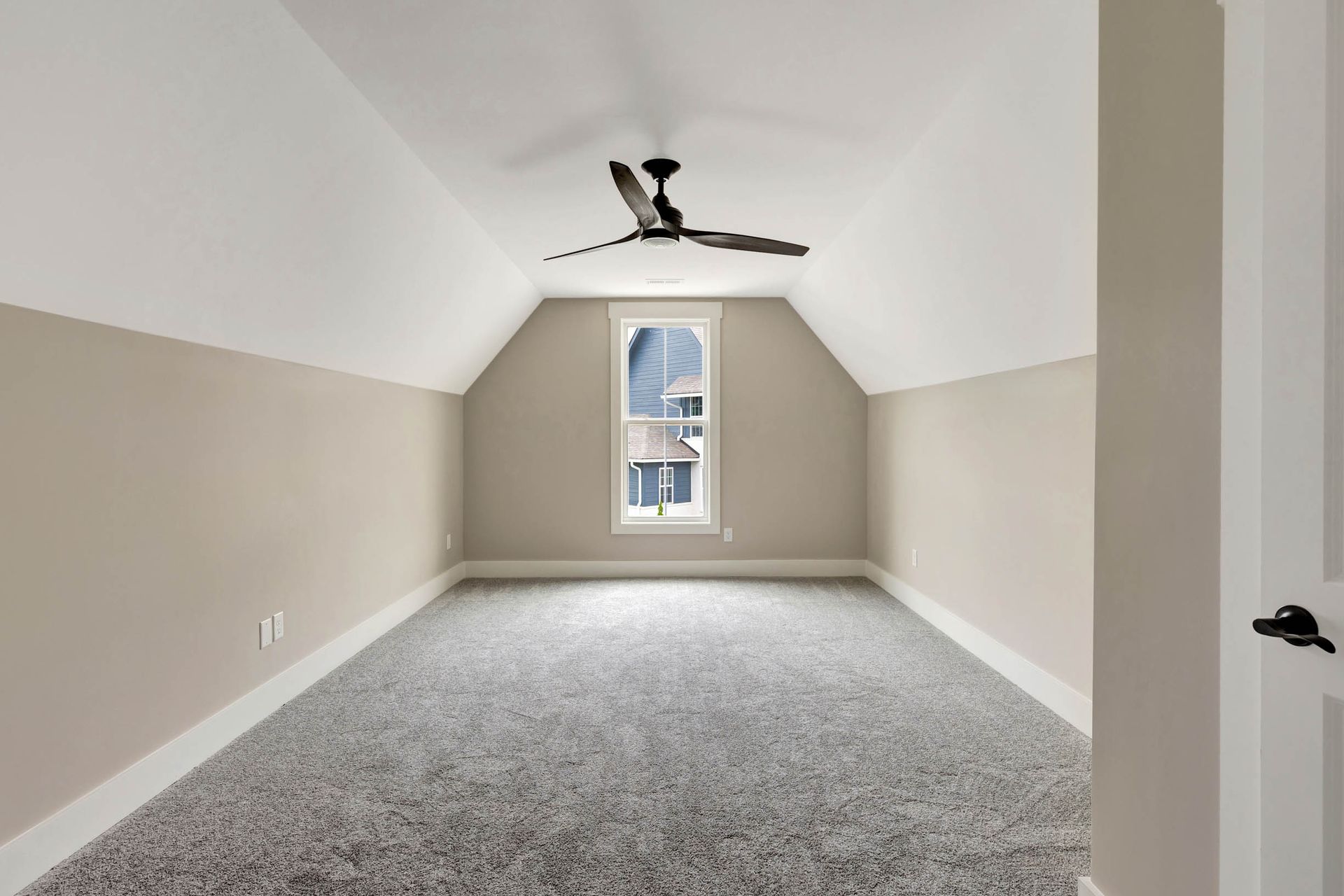 An empty room with a ceiling fan and a window.