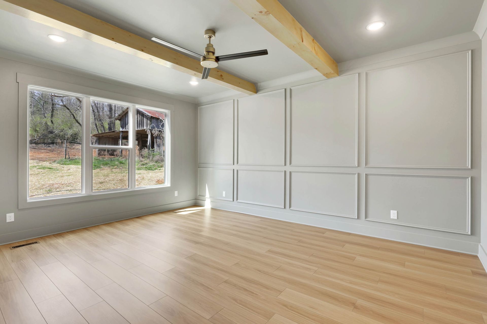 An empty living room with hardwood floors and a ceiling fan.