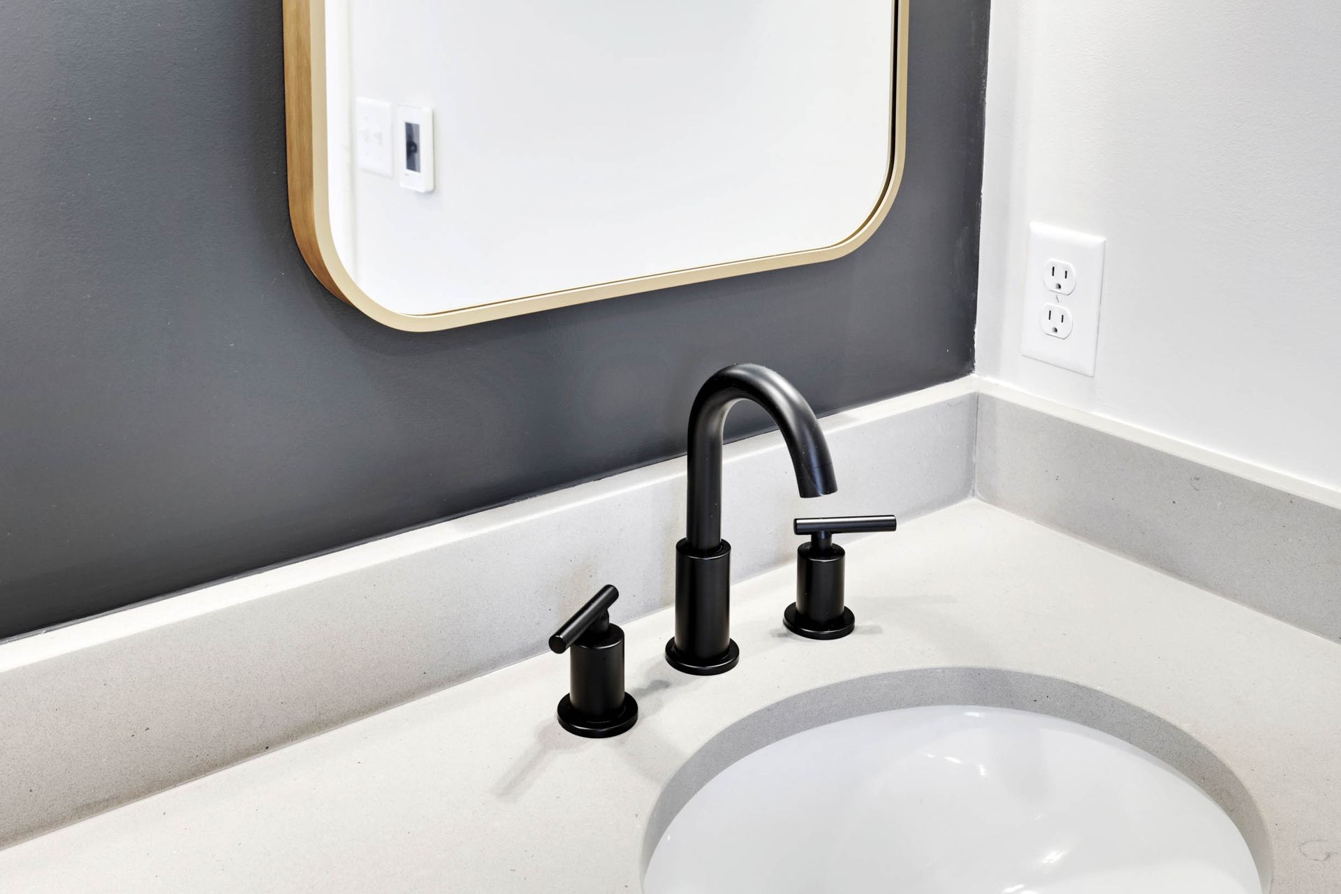 A bathroom sink with a mirror above it and a black faucet.