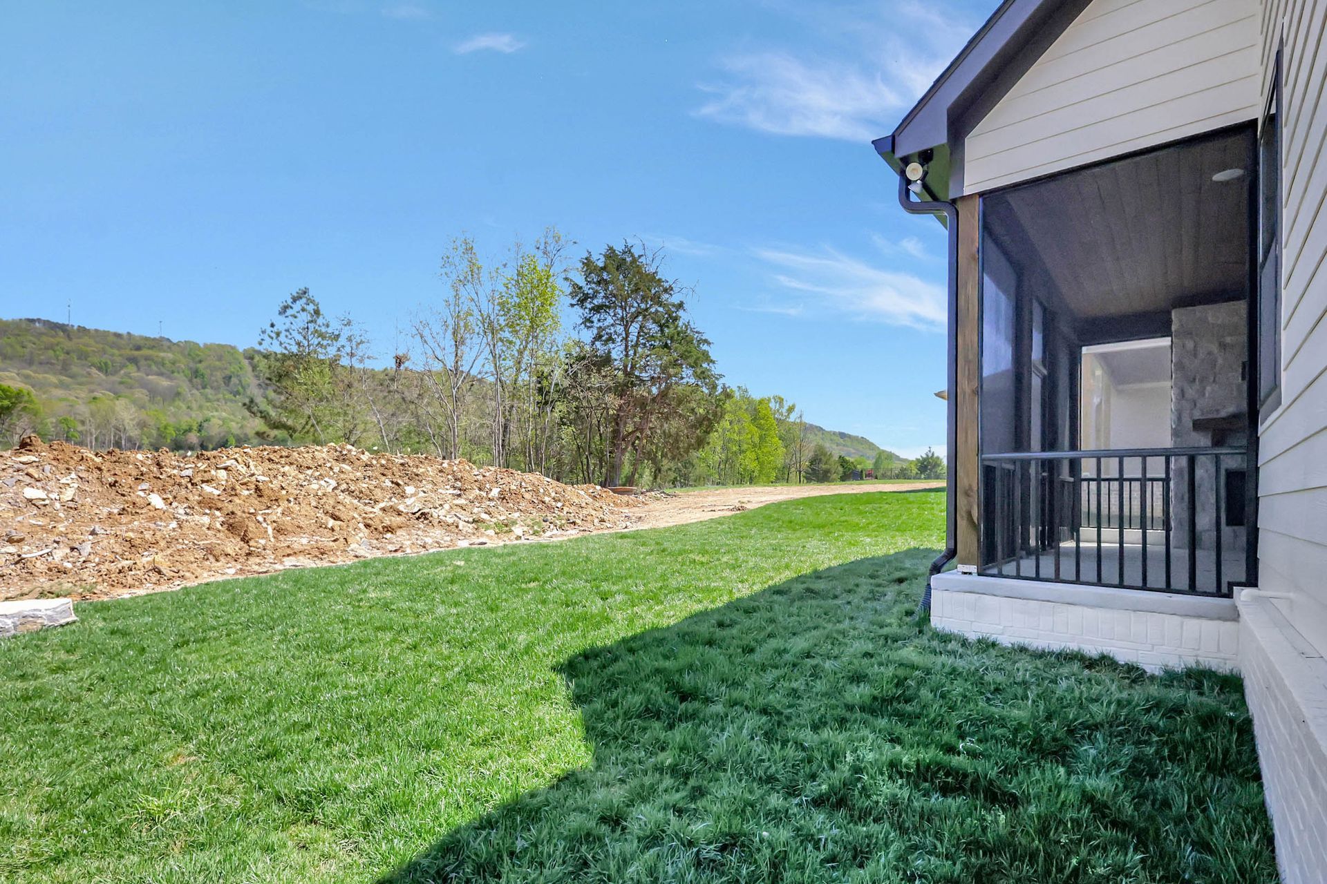 A house with a screened in porch and a large lawn in front of it.