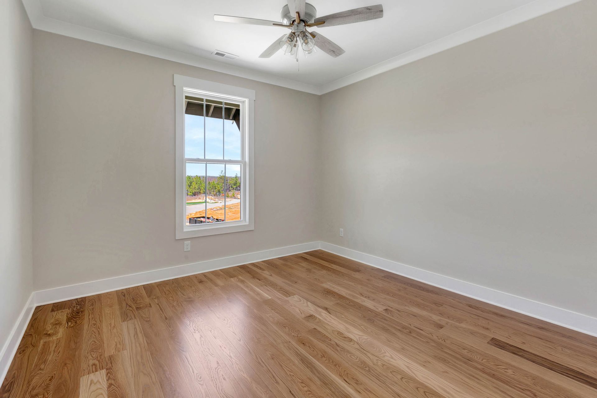 An empty room with hardwood floors and a ceiling fan.