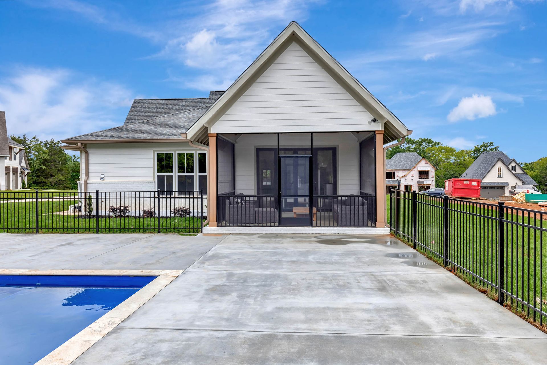 A house with a screened in porch and a swimming pool in front of it.
